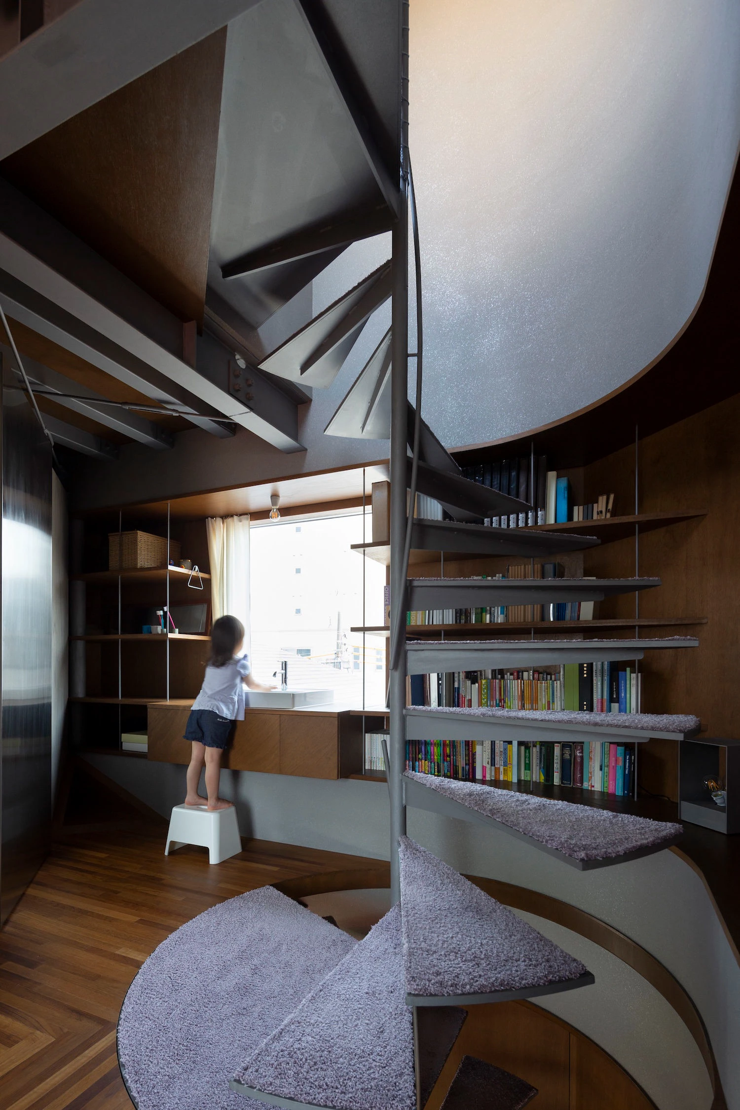 Bay Window Tower House by Takaaki Fuji + Yuko Fuji Architecture — Interior view of the stacked bay window tower, with a child standing on a white step stool to access the window ledge that serves as a functional...