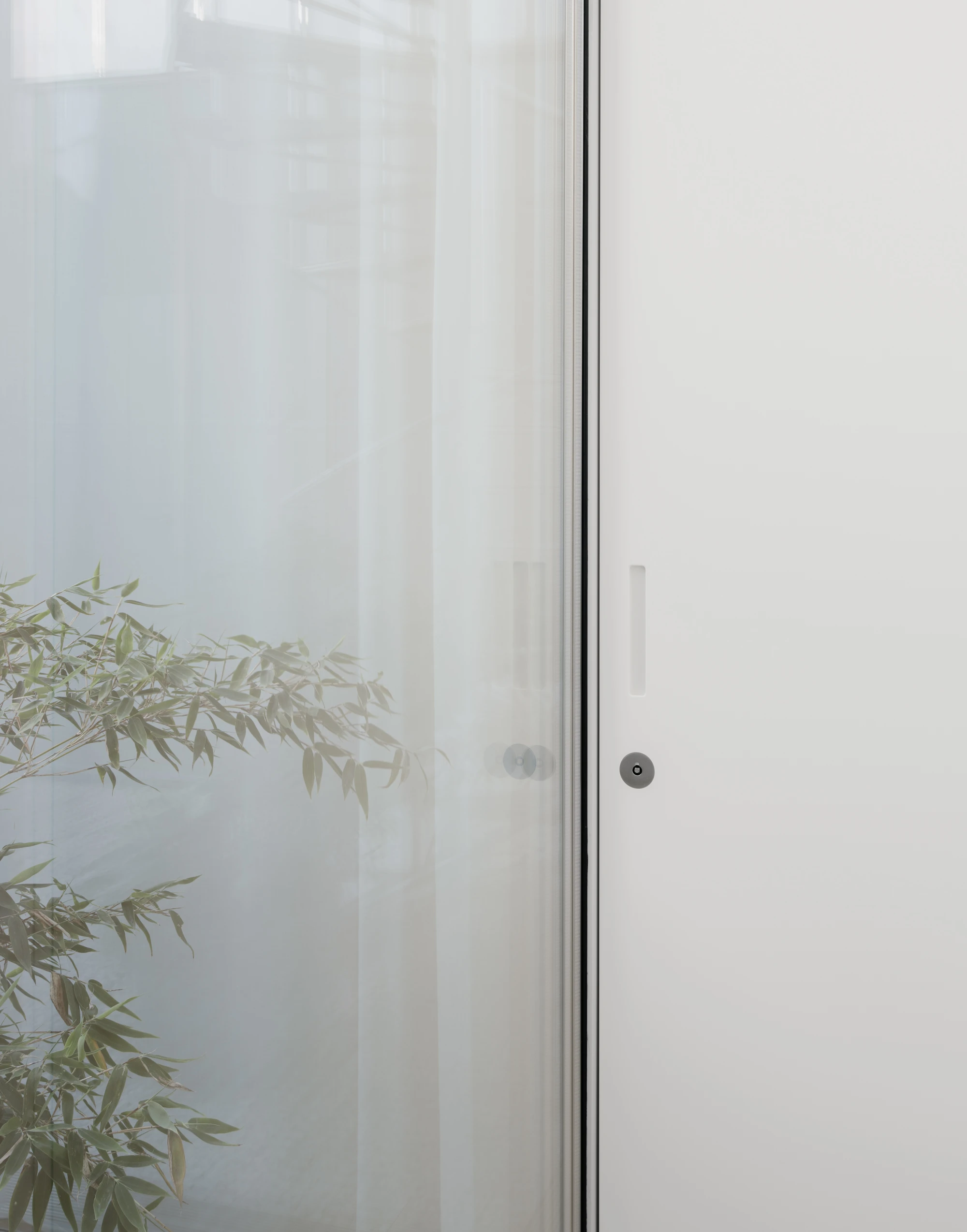 Ursulastraße 6 by Studio Mark Randel — A frameless glass sliding door with minimal aluminum mullion frames the threshold between exterior and interior spaces.