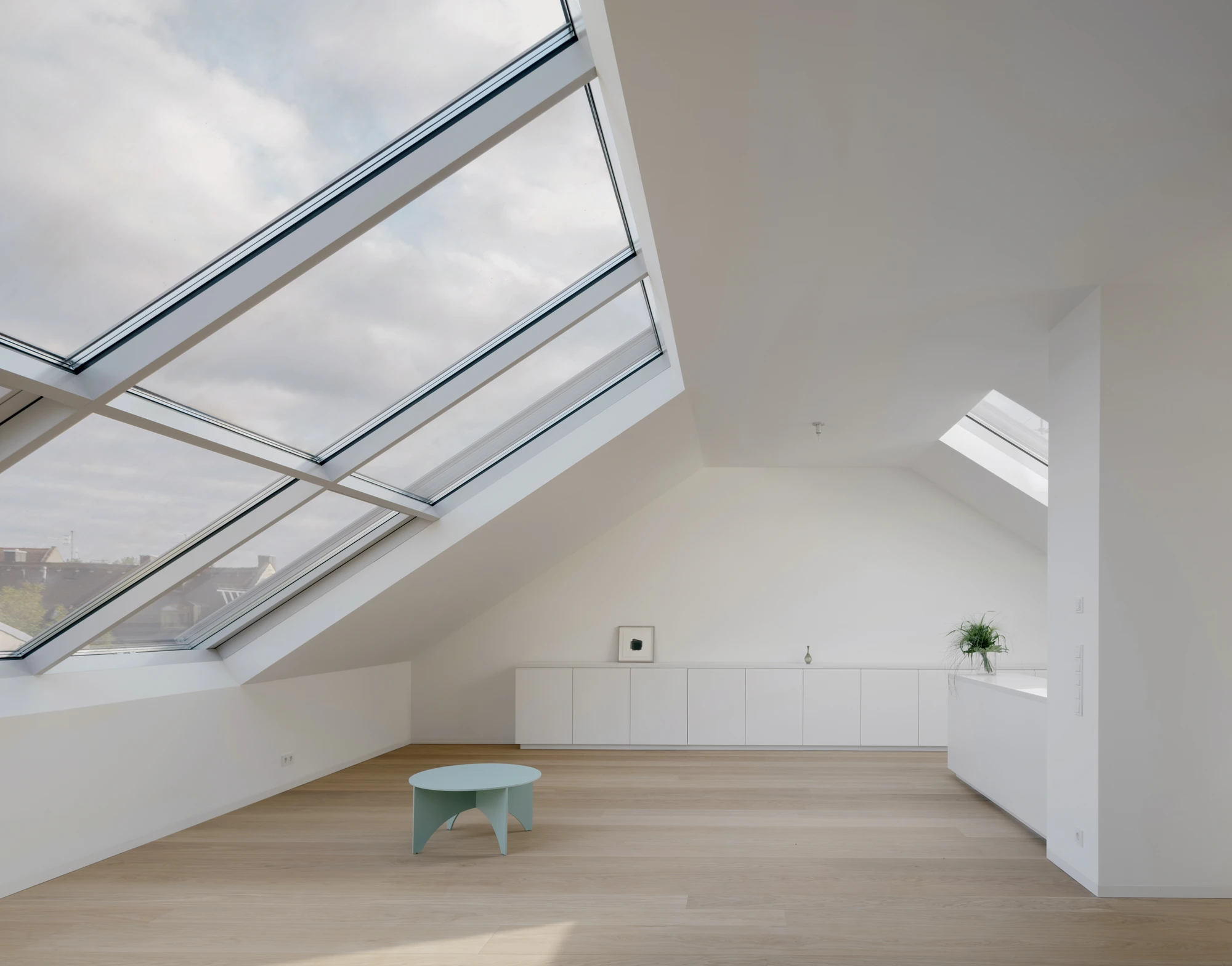 Ursulastraße 6 by Studio Mark Randel — A pitched attic space in Munich's Altschwabing, flooded with natural light through two large skylights with aluminum framing.