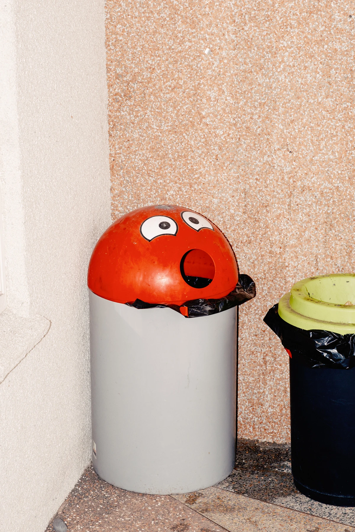 Lupine by Daniel Dorsa — A anthropomorphized trash bin constructed from a white cylindrical container topped with a red dome featuring exaggerated cartoon eyes and an open mouth.
