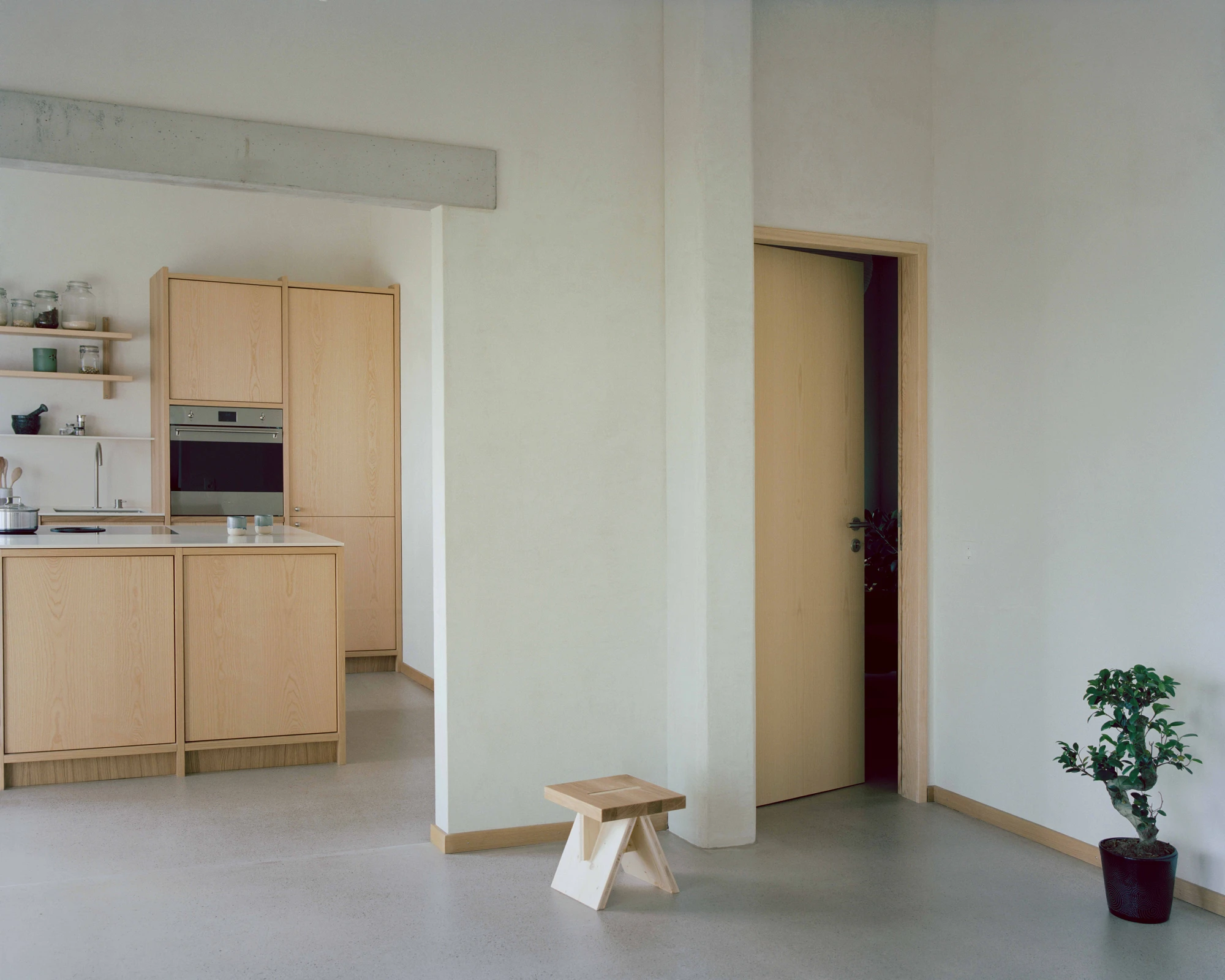 Family Villa by Noue Studio — The reconfigured interior reveals the spatial strategy through a single composition: a white cylindrical column divides the open plan, framing views toward...