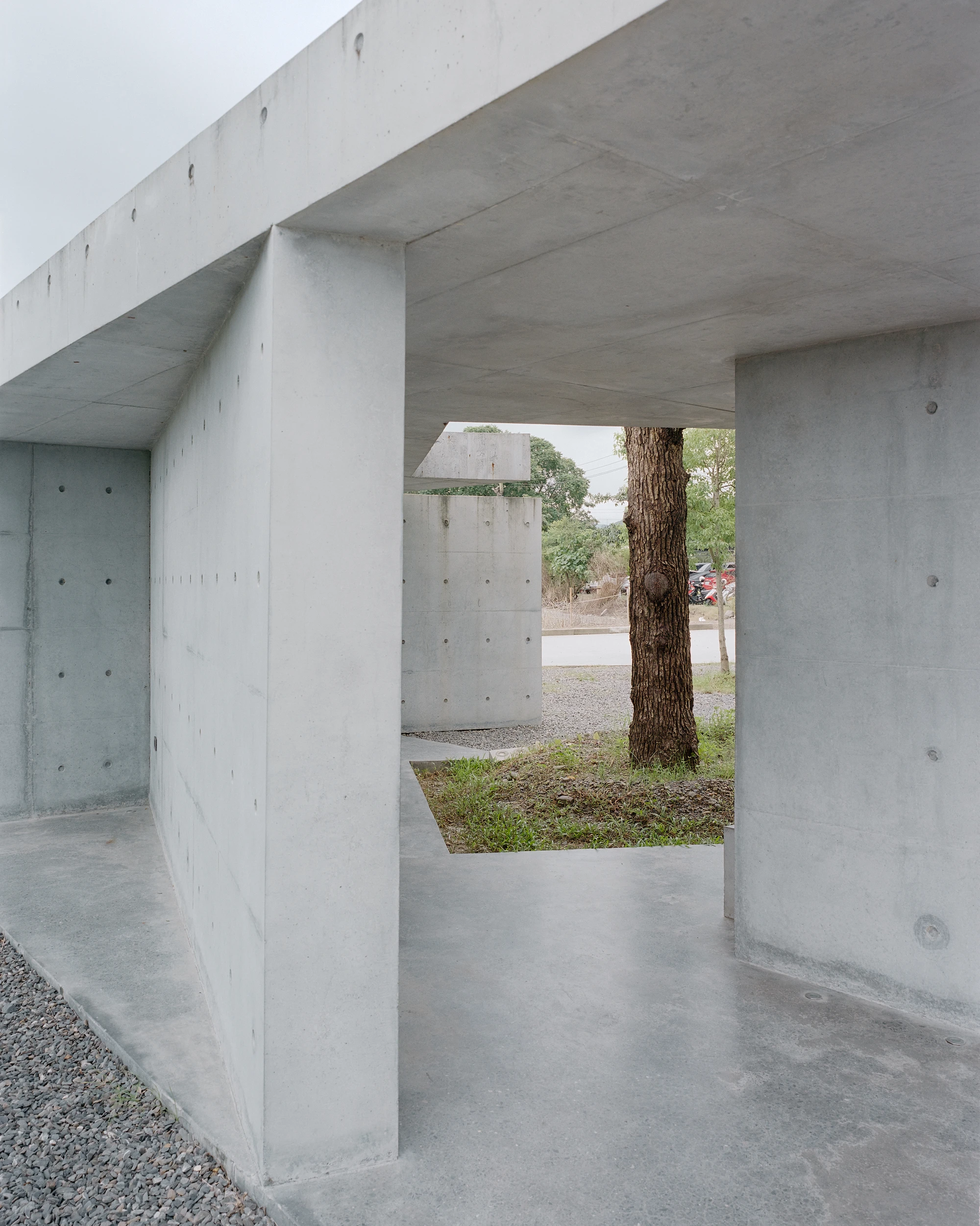 Entry Pavilion by metrics architecture studio — The Entry Pavilion's interior reveals a monolithic concrete structure defined by exposed aggregate walls punctuated with a regular perforation pattern.