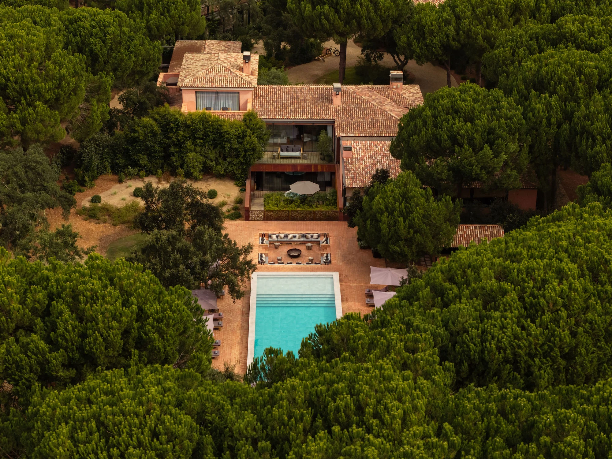 Sublime Comporta — Aerial view of a residential complex nestled within a dense pine forest, revealing the architectural strategy for minimal landscape disruption.