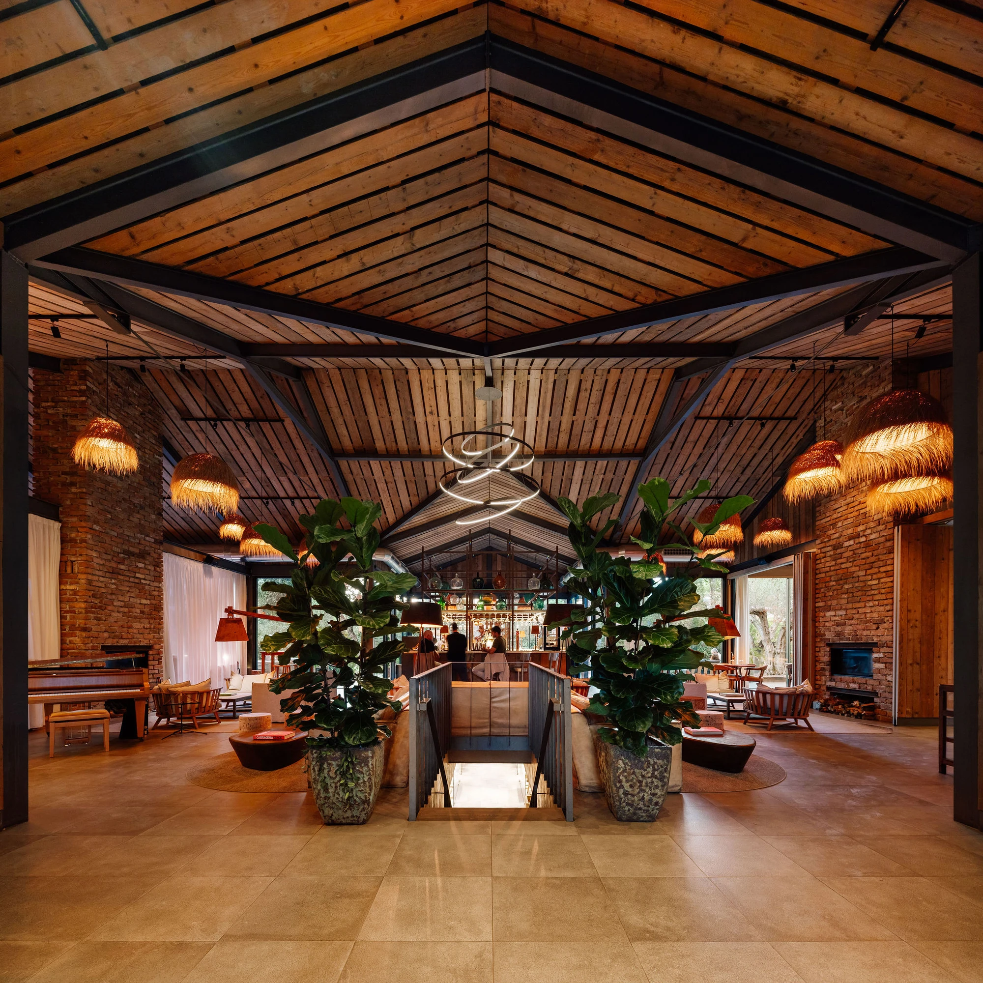 Sublime Comporta — A symmetrical interior view of Sublime Comporta's central pavilion reveals timber beam construction beneath a pitched roof with skylights.