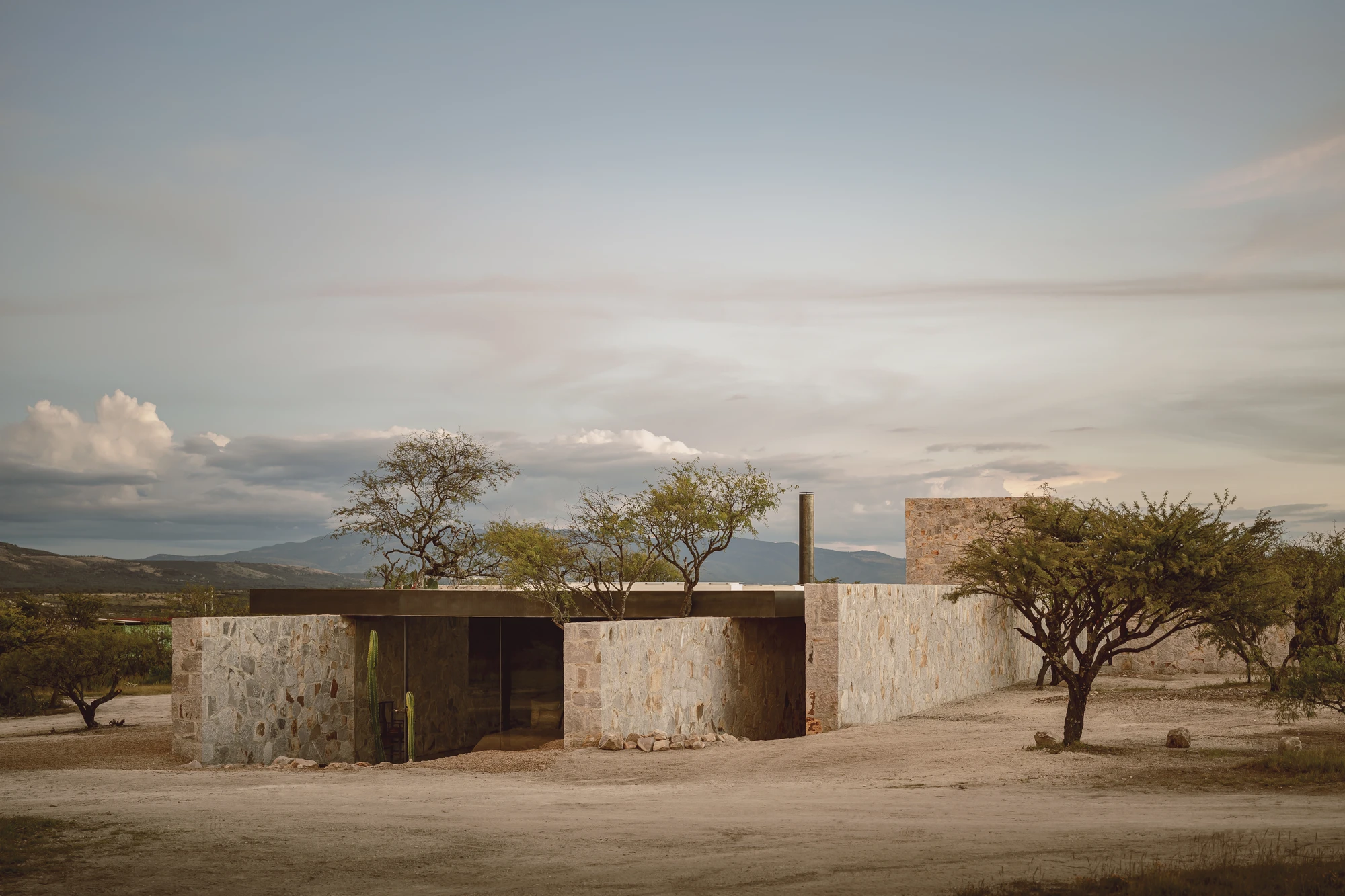 Enso House II by HW Studio — HW Studio's cruciform residence emerges from the mesquite-scattered plateau as a cluster of coursed stone volumes, their weathered surfaces stratified in...