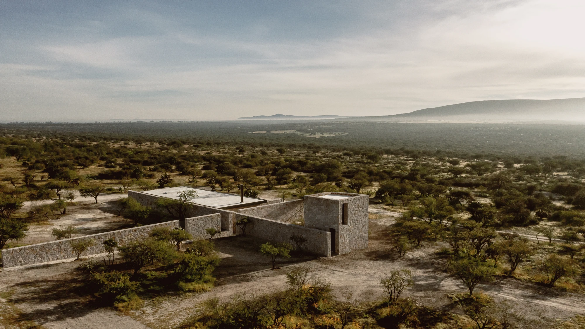 Enso House II by HW Studio — Enso House II emerges from the mesquite-dotted landscape as a coursed stone cruciform, its thick masonry walls articulated by horizontal stratification that...