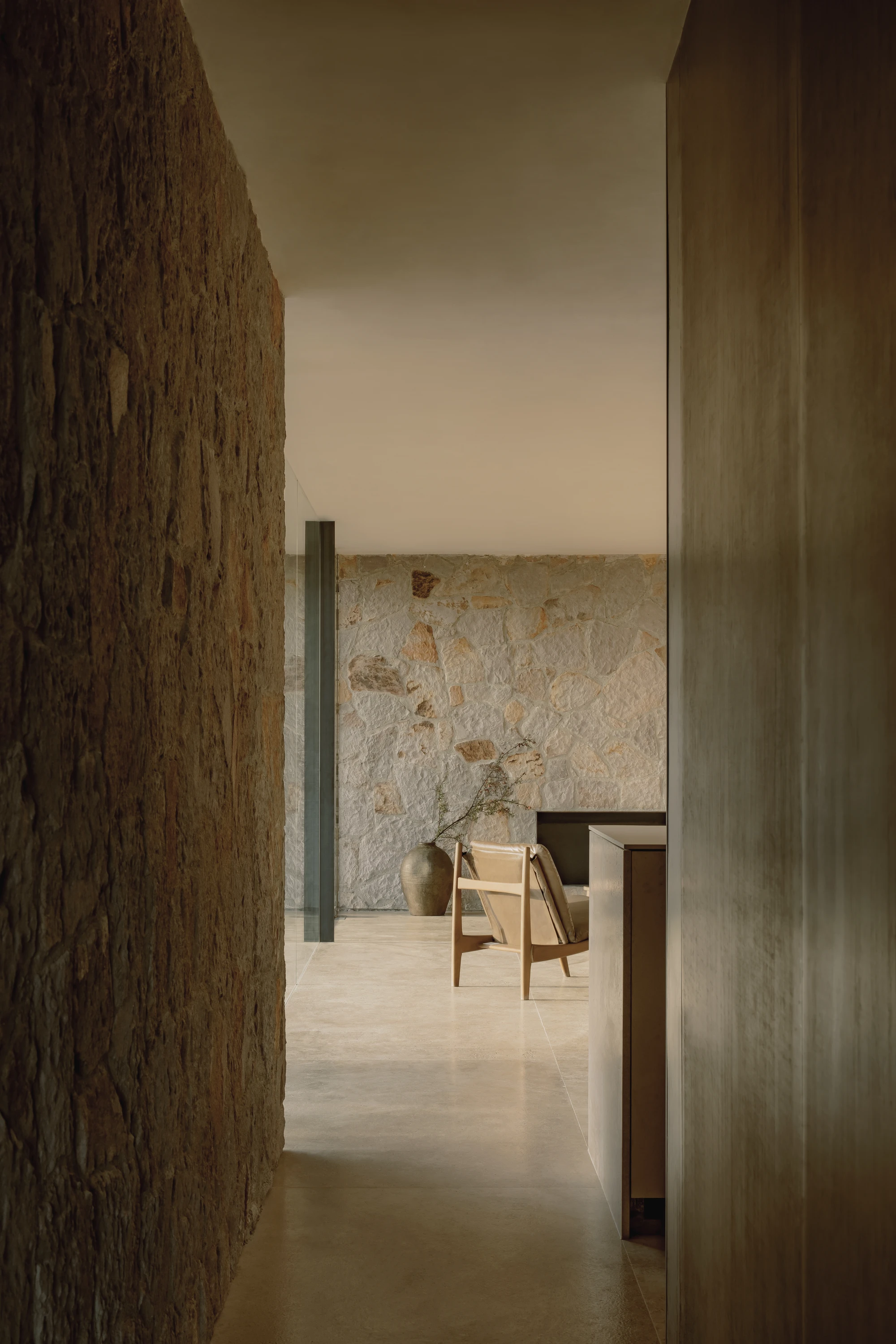 Enso House II by HW Studio — A narrow passage frames the interior courtyard beyond, with coursed stone walls on either side creating a threshold experience.