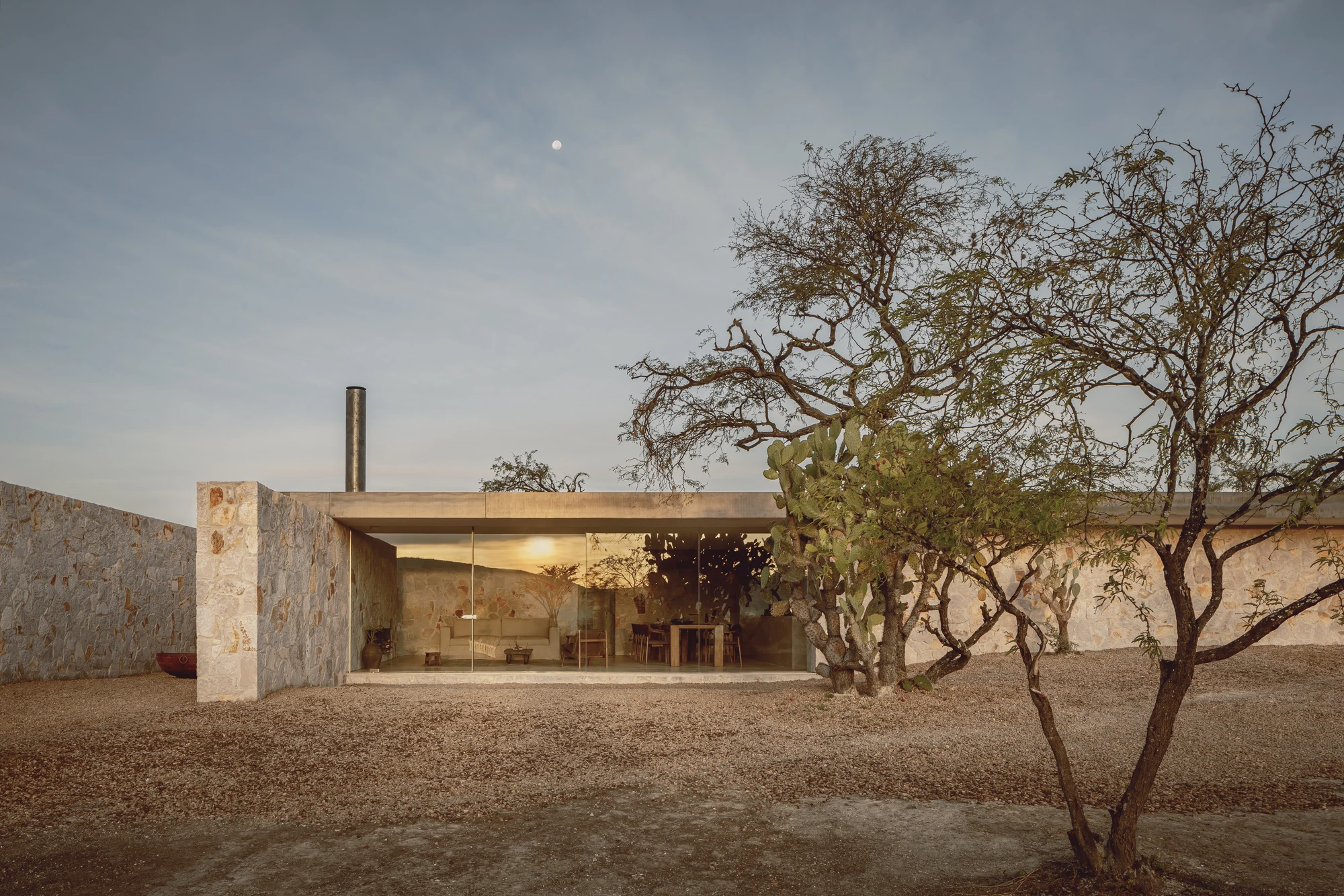 Enso House II by HW Studio — HW Studio's cruciform residence presents itself across the San Miguel de Allende landscape through a gridded glass facade set within thick coursed stone walls.