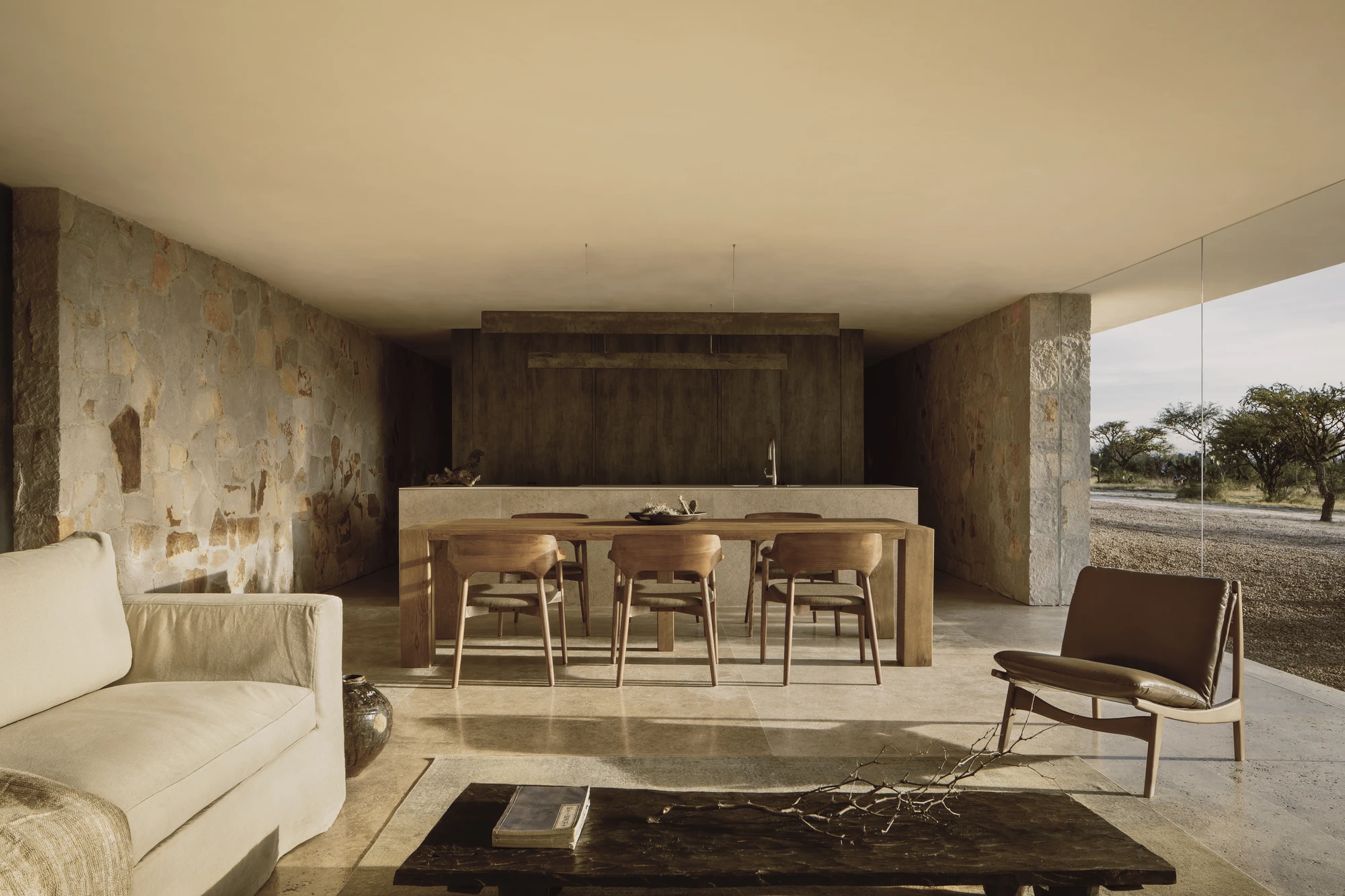Enso House II by HW Studio — A cruciform residence in San Miguel de Allende presents its interior living zone through floor-to-ceiling glazing, framing the mesquite-dotted landscape beyond.