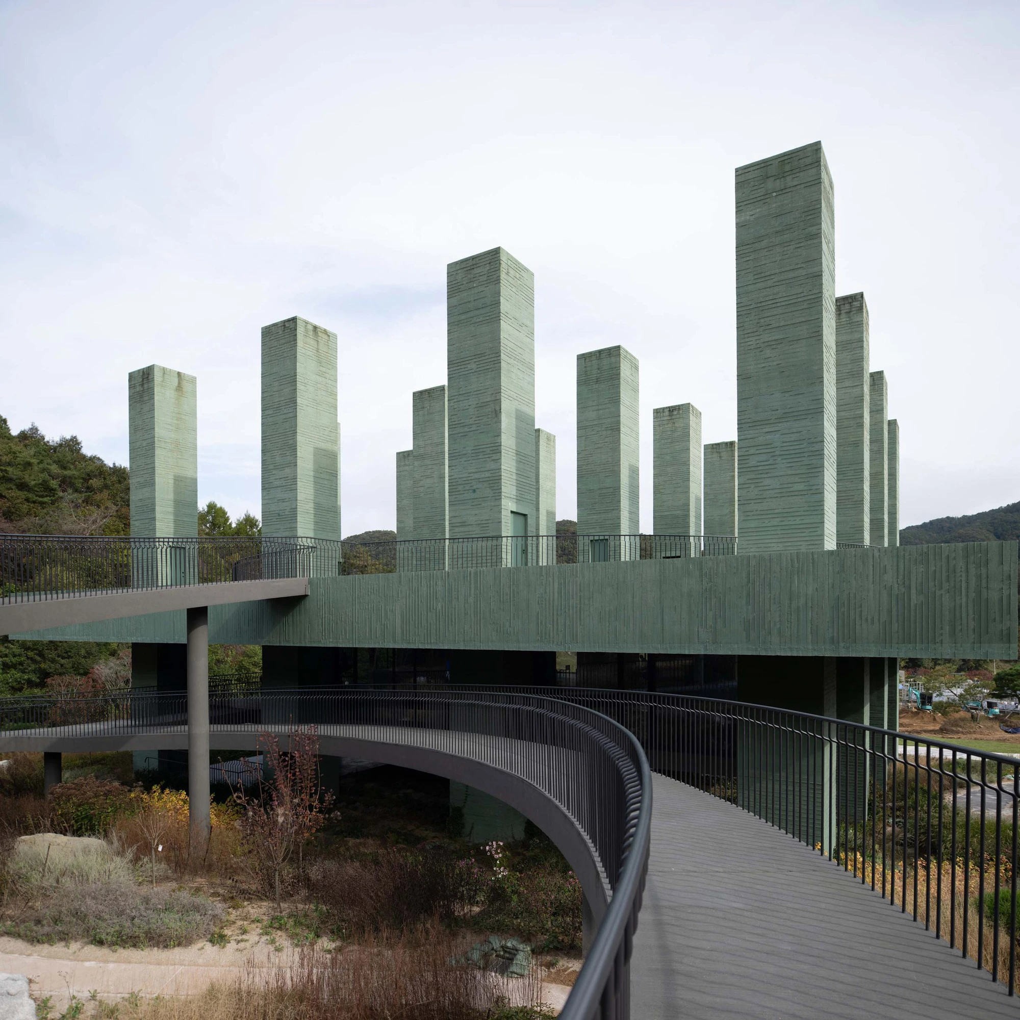 REST Garden Restaurant by Pezo von Ellrichshausen — Nine monolithic concrete columns arranged in a strict orthogonal grid rise from an elevated platform cantilevered above sloped terrain.