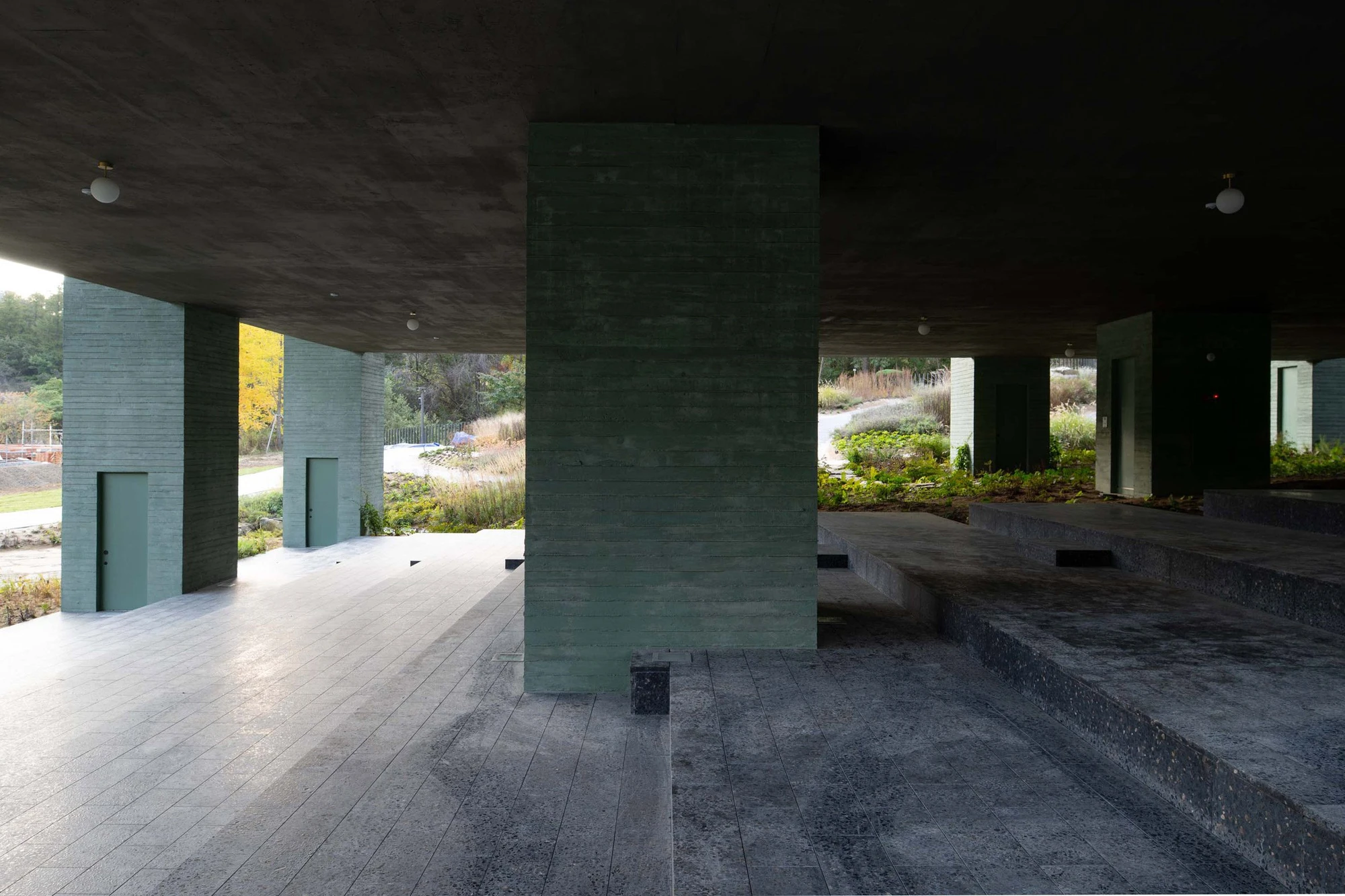 REST Garden Restaurant by Pezo von Ellrichshausen — Nine tapered concrete columns arranged in strict orthogonal grid support a continuous ceiling plane that cantilevered over sloped terrain, creating a...
