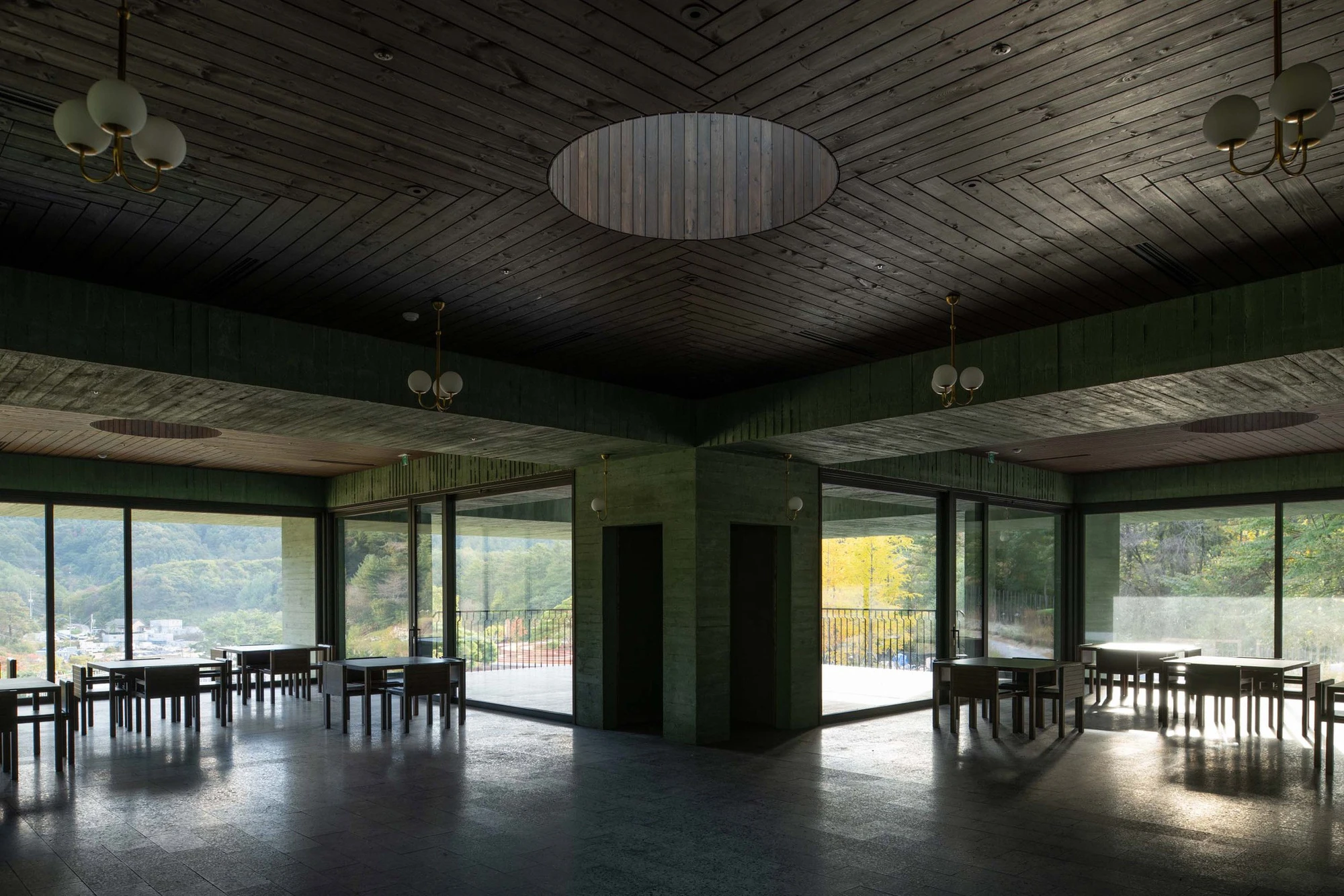 REST Garden Restaurant by Pezo von Ellrichshausen — A dining hall organized around a central monolithic concrete core, its green-tinted surface articulated with dark vertical striping.