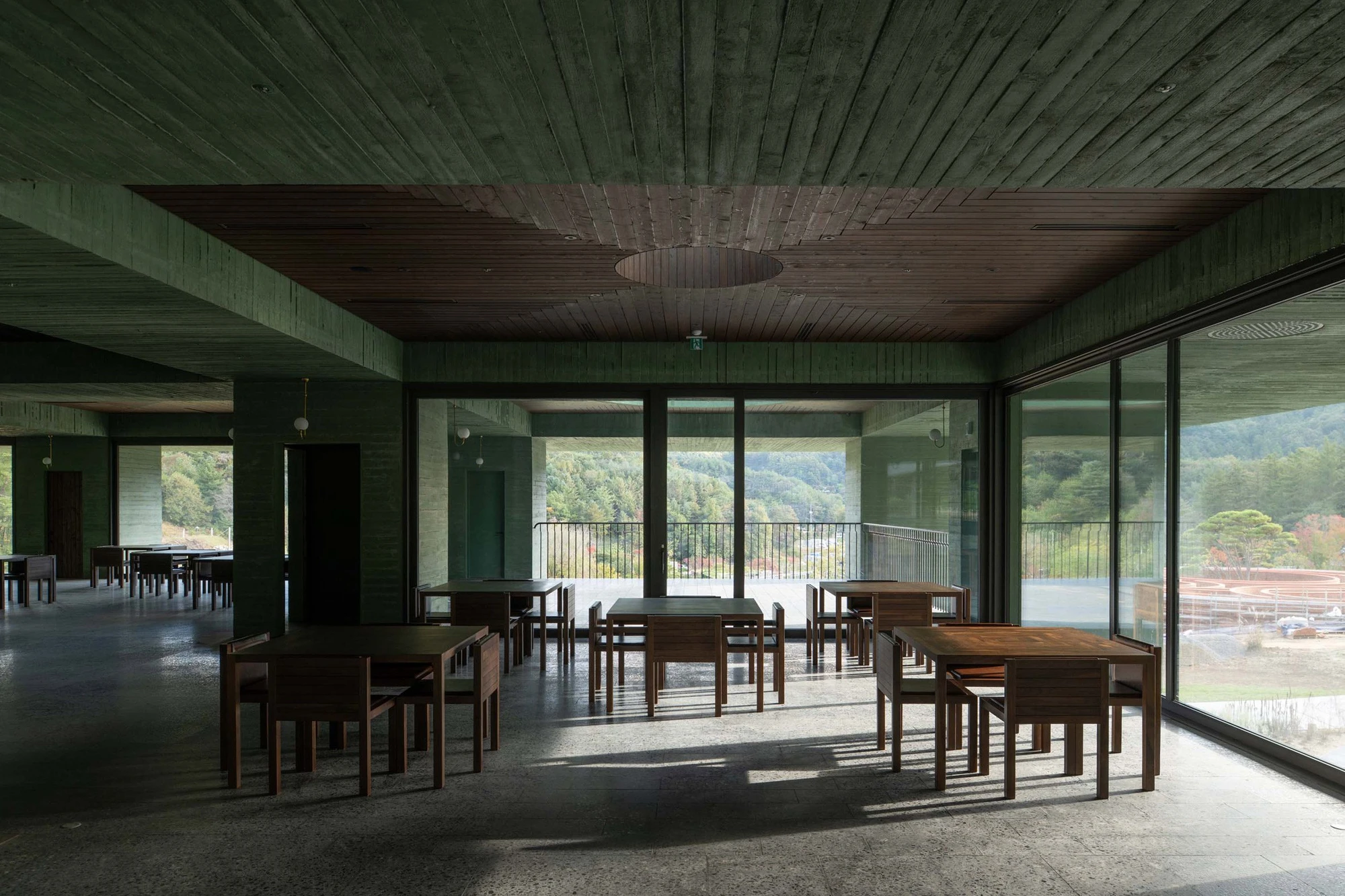 REST Garden Restaurant by Pezo von Ellrichshausen — The dining hall unfolds beneath a continuous timber ceiling, nine concrete columns arranged in strict orthogonal grid supporting the horizontal plane overhead.