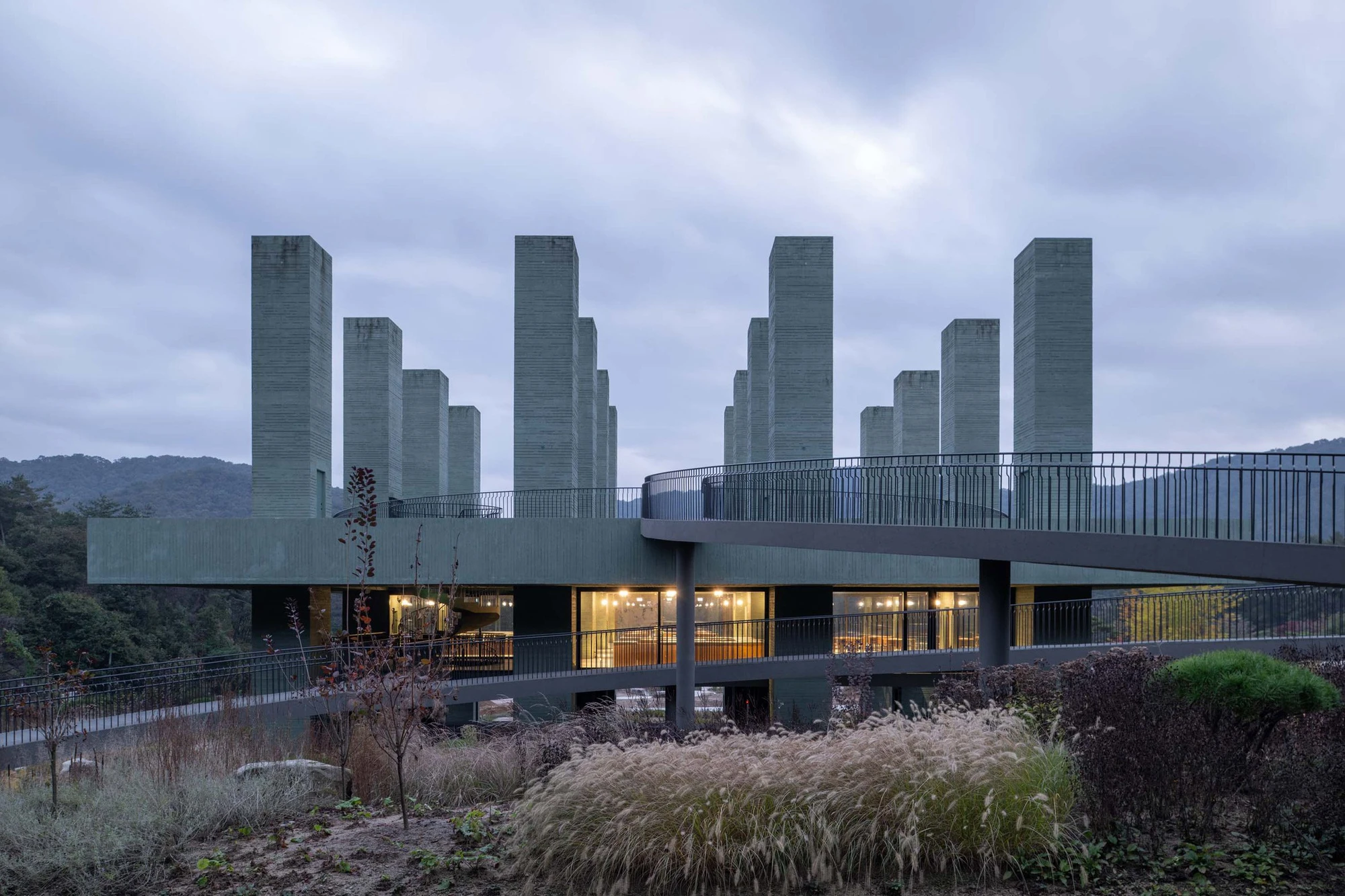 REST Garden Restaurant by Pezo von Ellrichshausen — Nine rectangular concrete columns rise in strict orthogonal grid from an elevated platform cantilevered above sloped terrain.