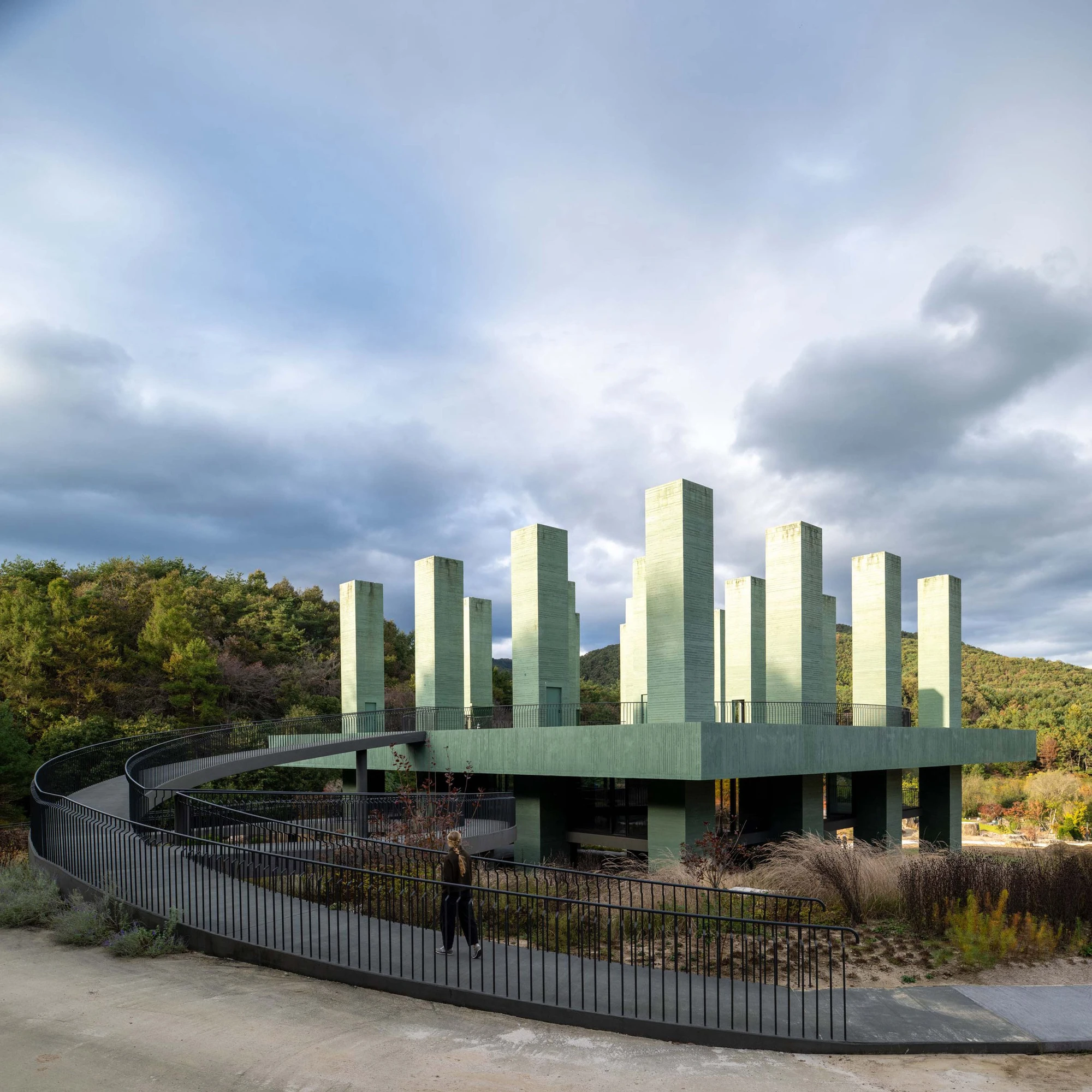 REST Garden Restaurant by Pezo von Ellrichshausen — Nine vertical concrete columns arranged in a strict orthogonal grid rise from an elevated platform cantilevered above sloped terrain.