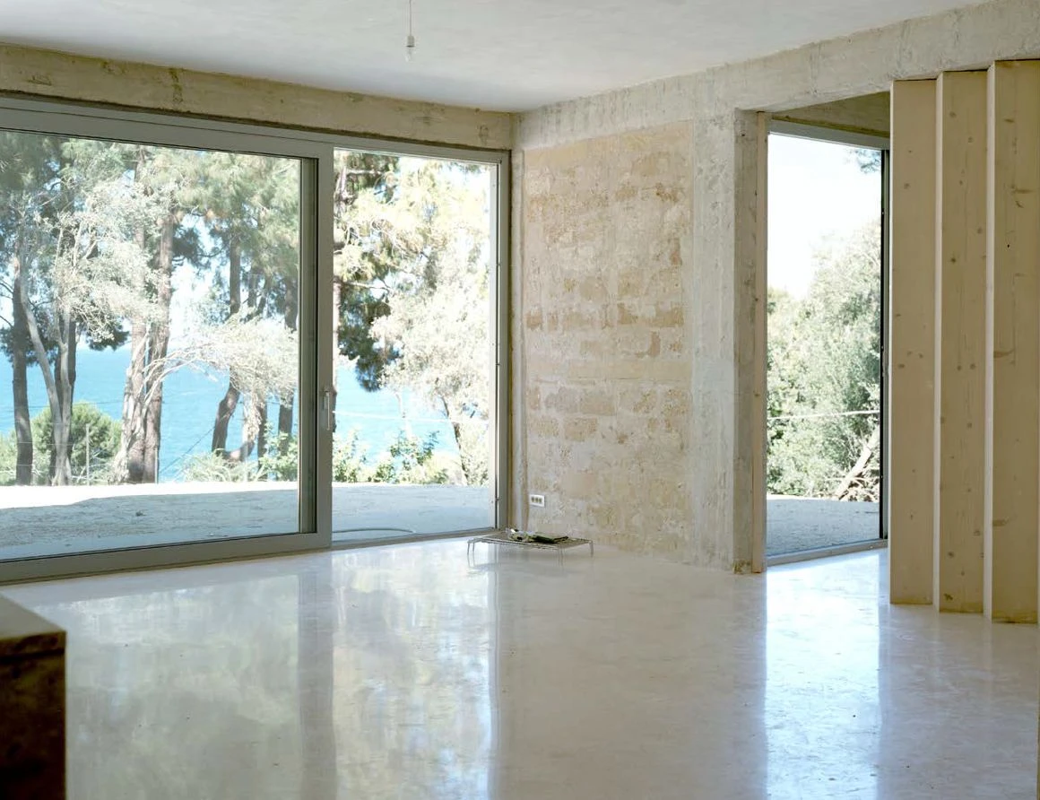 Guardia di Finanza by Brandlhuber+ — Interior view of the renovated Guardia di Finanza station reveals a stripped concrete structural frame infilled with local tufa stone between bays.