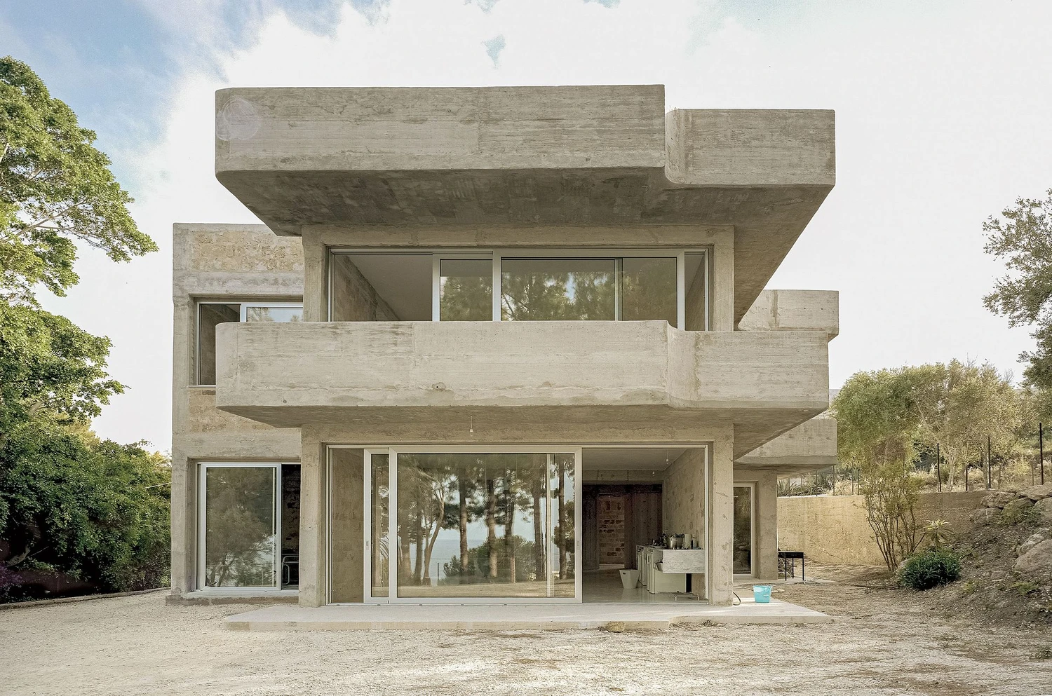 Guardia di Finanza by Brandlhuber+ — The renovated Guardia di Finanza station presents its south-facing elevation in full daylight, revealing board-formed concrete structural bays infilled with...