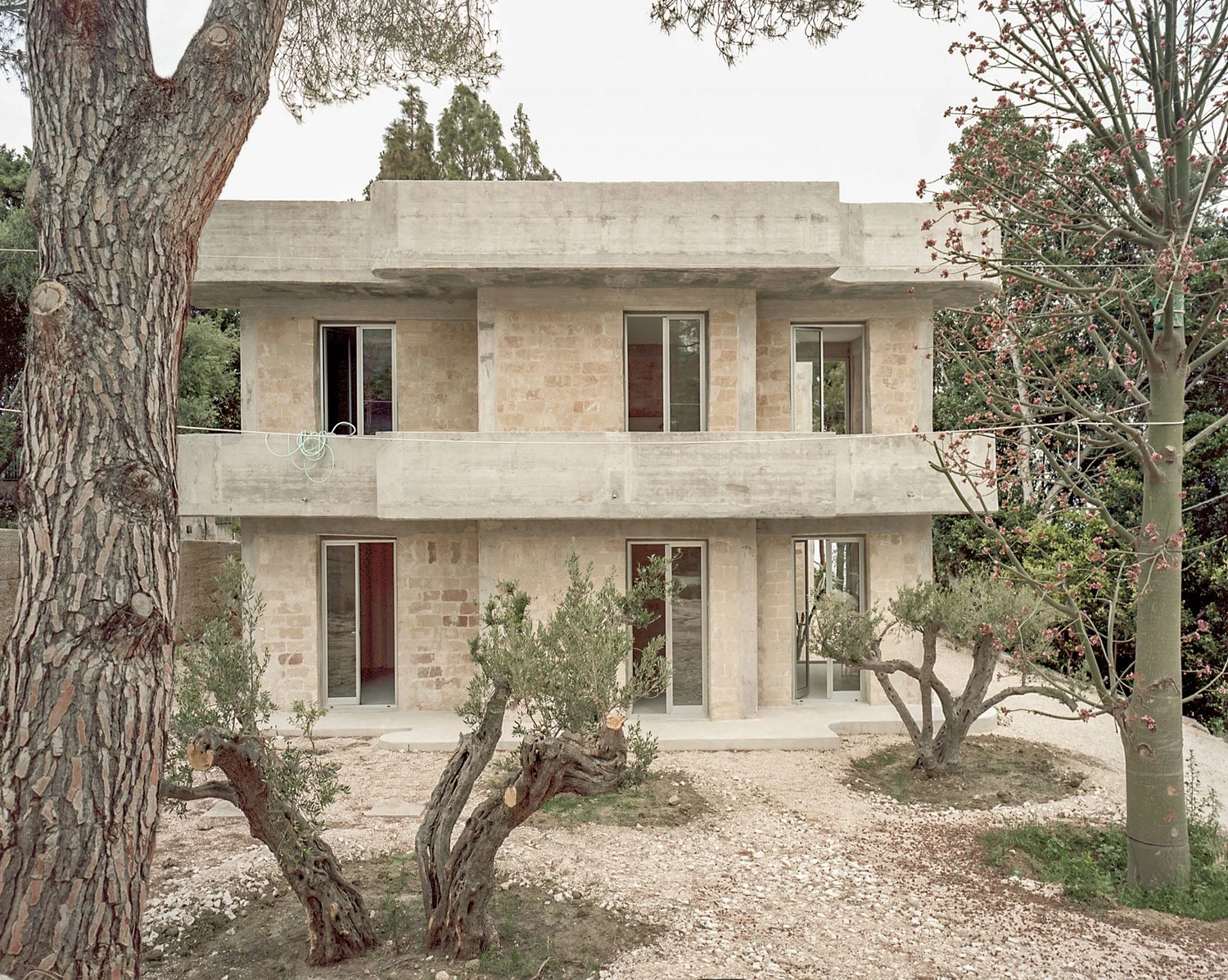 Guardia di Finanza by Brandlhuber+ — The courtyard elevation of the 1976 Guardia di Finanza station reveals its structural logic: a reinforced concrete frame with board-formed surfaces infilled...