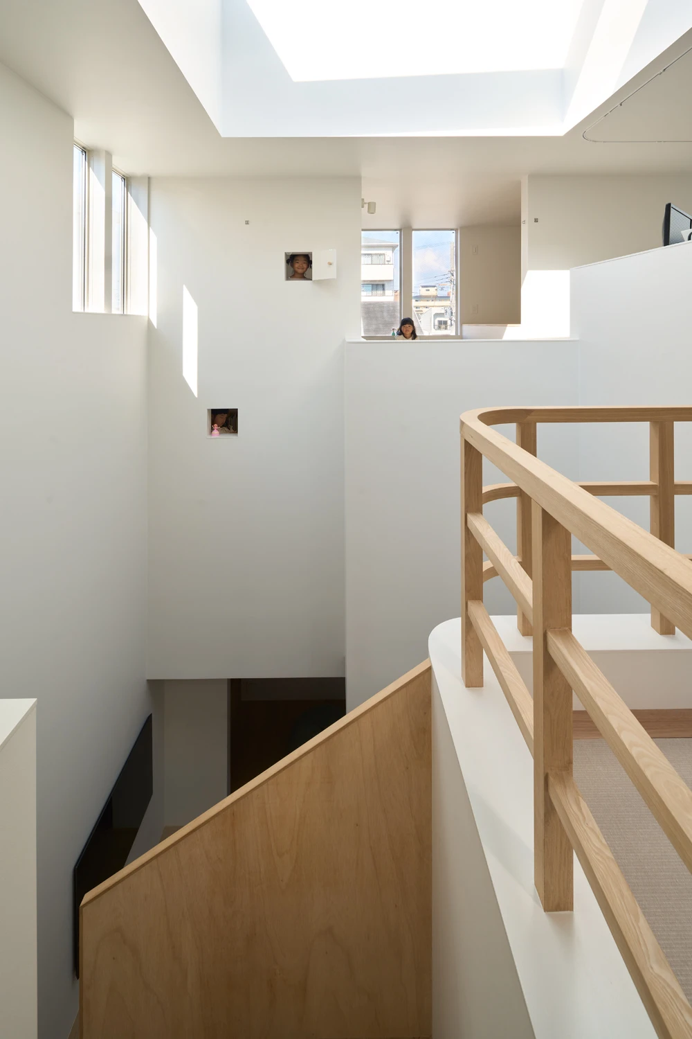 House in Hirano by Fujiwaramuro Architects — A multi-story stairwell with natural light from above floods the white interior, revealing the vertical compression strategy of this flagpole-lot dwelling.