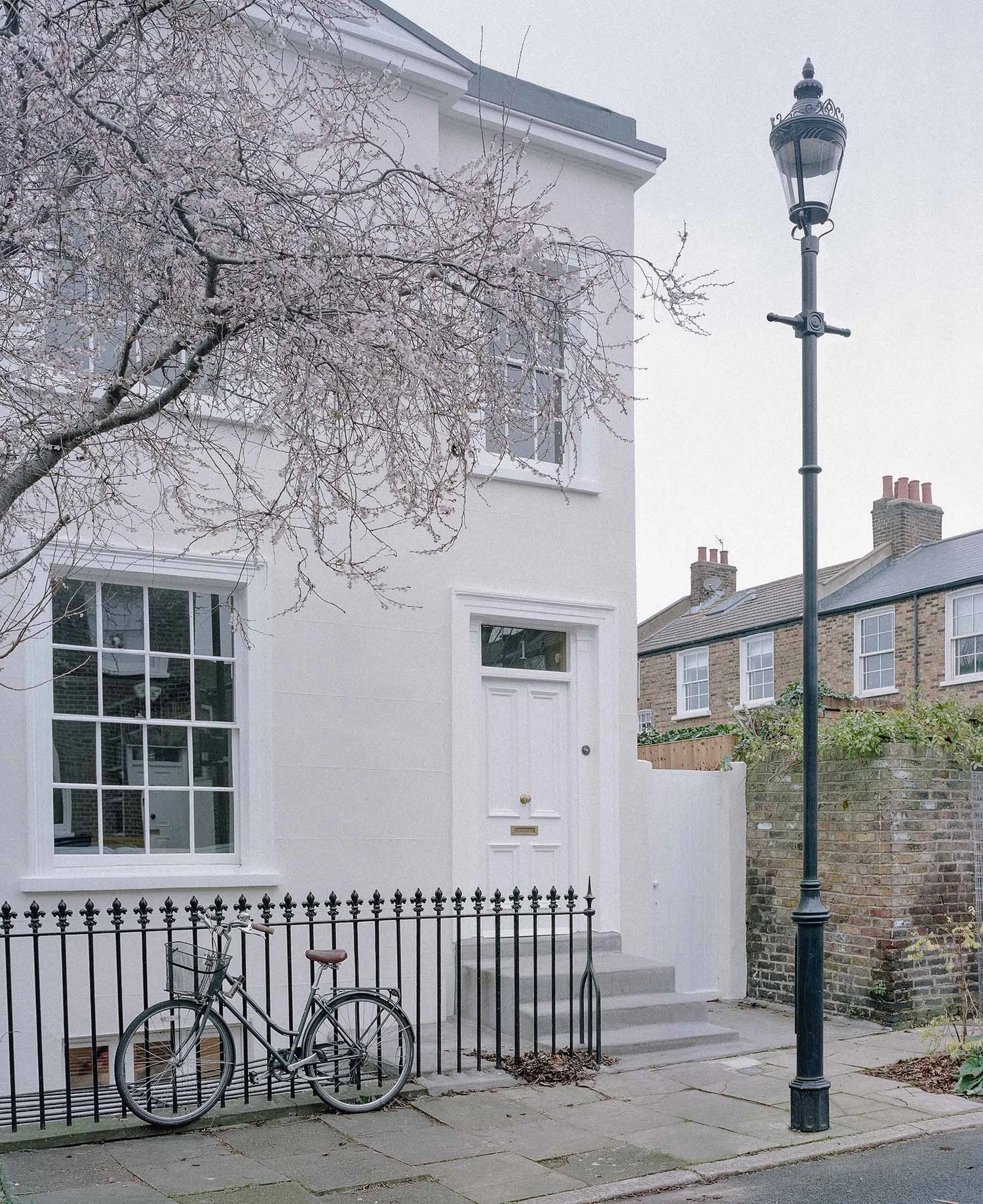Barnsbury House by Architecture for London — The street facade of Barnsbury House presents a restrained Georgian intervention with a rendered white exterior and multi-paned glazed window with...