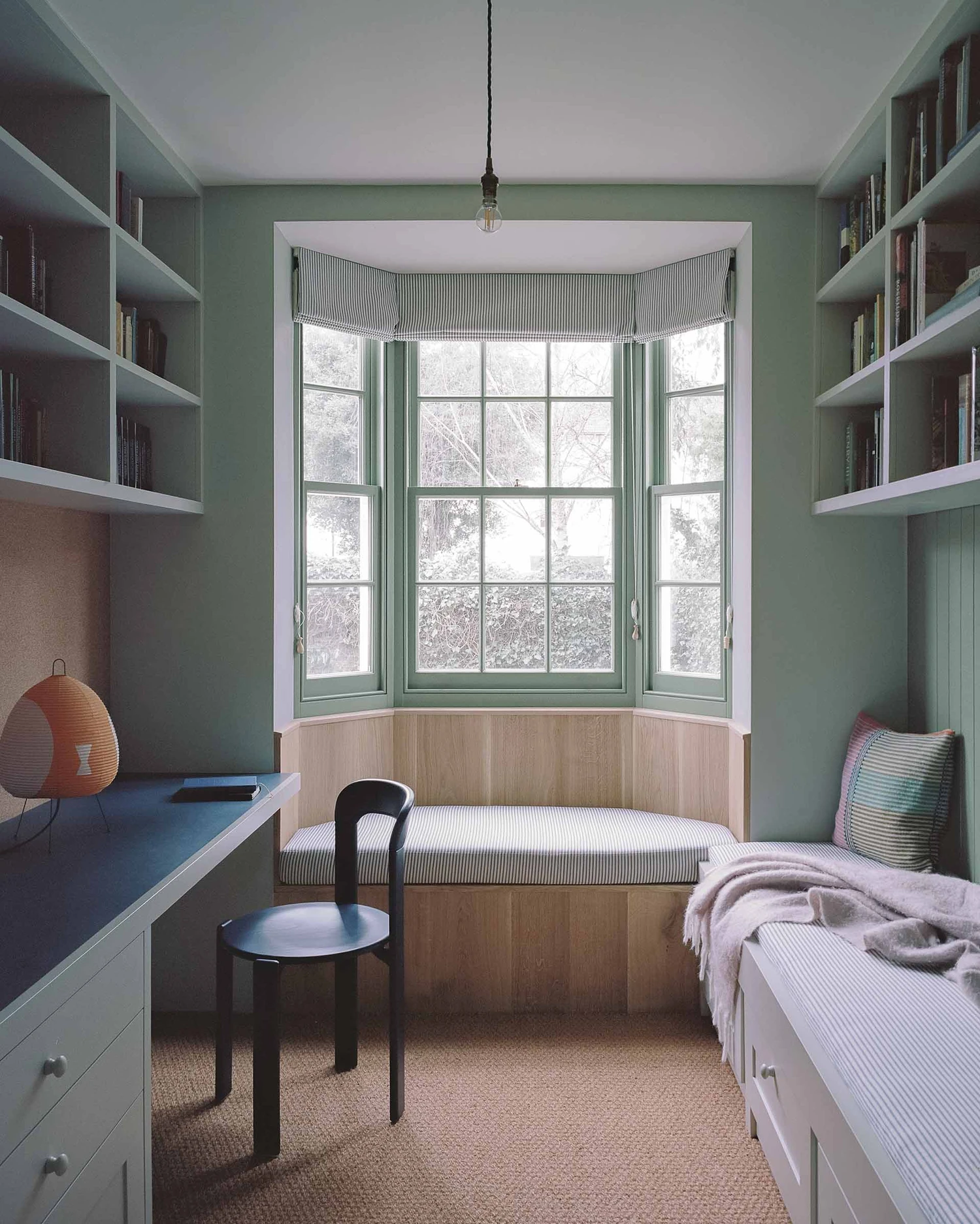 Barnsbury House by Architecture for London — A bedroom designed as a study alcove, anchored by a bay window with green-painted timber frames and multi-paned glazing.