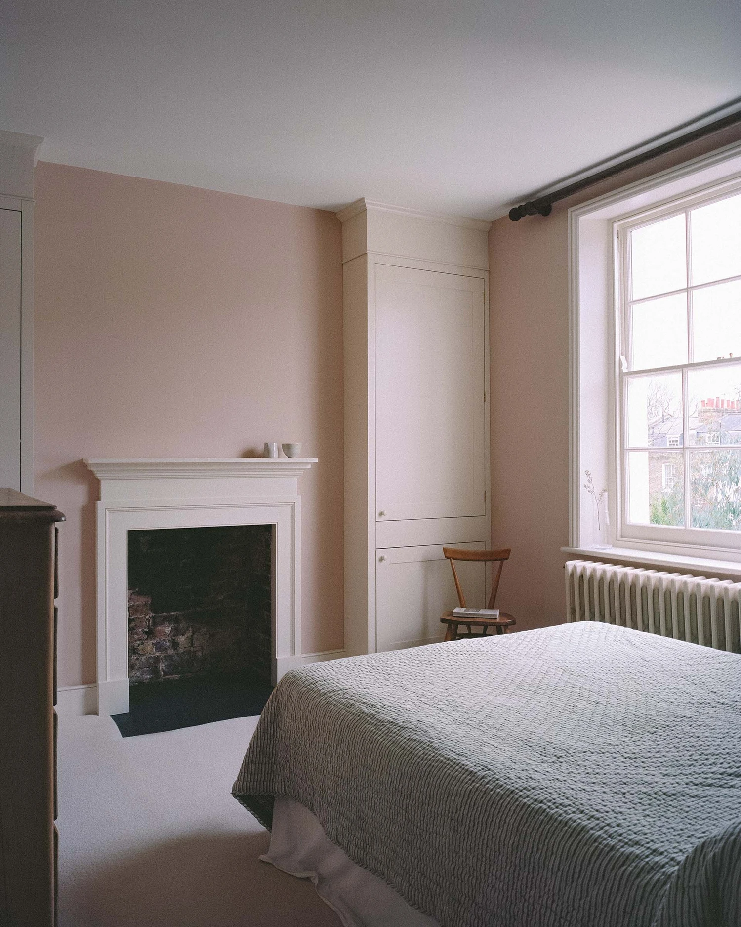 Barnsbury House by Architecture for London — A bedroom in the Grade II listed Georgian townhouse featuring a cream-painted fireplace with dark inset and white surround positioned against a...