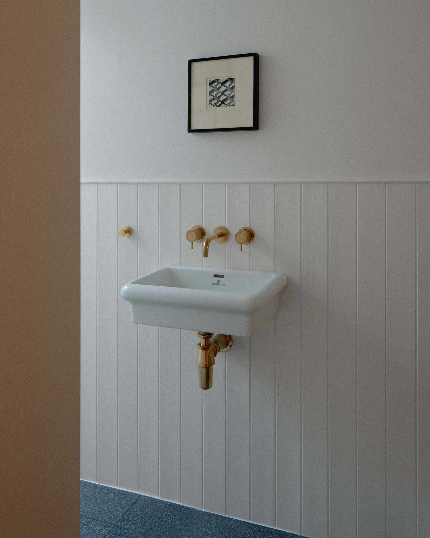 Barnsbury House by Architecture for London — A bathroom detail showing wall-mounted brass fittings against white vertical tongue-and-groove paneling.