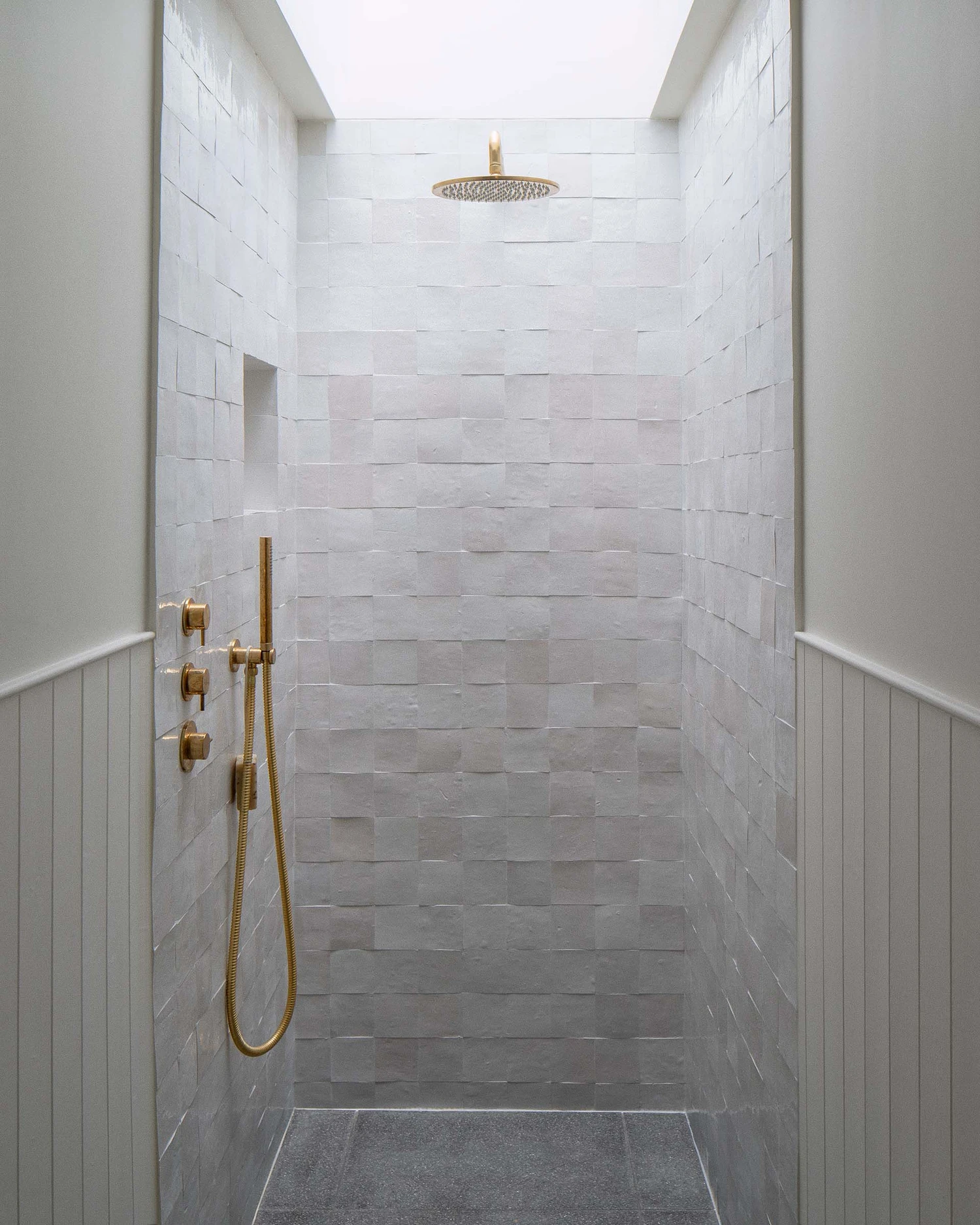 Barnsbury House by Architecture for London — A walk-in shower lined with stacked-bond white tile in horizontal courses, creating subtle tonal variation across the walls.