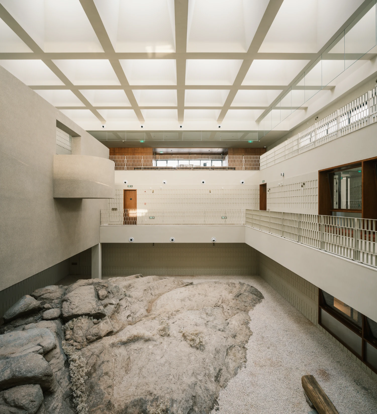 Lost Villa Shengsi Huanglong Island Lighthouse Hotel by SZ-Architects — An enclosed atrium frames a raw granite boulder and loose sand against refined architectural geometry.