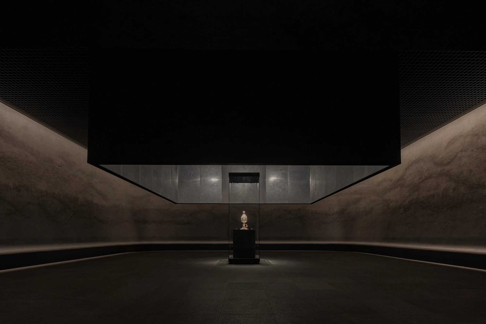 Baekje Gilt Bronze Incense Burner Hall (Buyeo National Museum) by WGNB — A monolithic concrete hall frames a single gilt bronze object on a central plinth, positioned within a curved chamber defined by board-formed concrete walls...