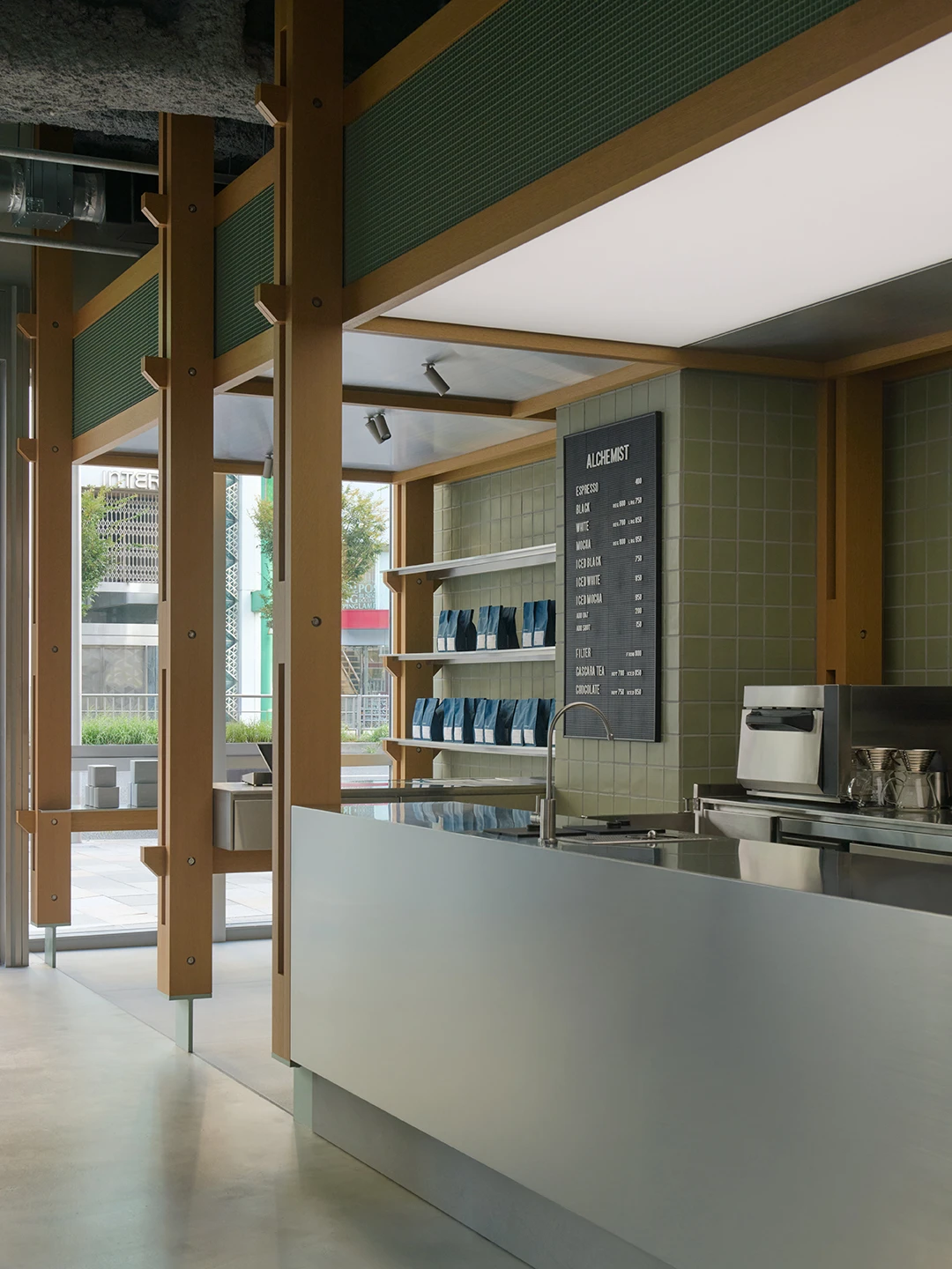 Alchemist Aoyama by Wynk Collaborative — The Alchemist Aoyama counter materializes as a pavilion defined by rhythmic wooden columns in warm timber tones.