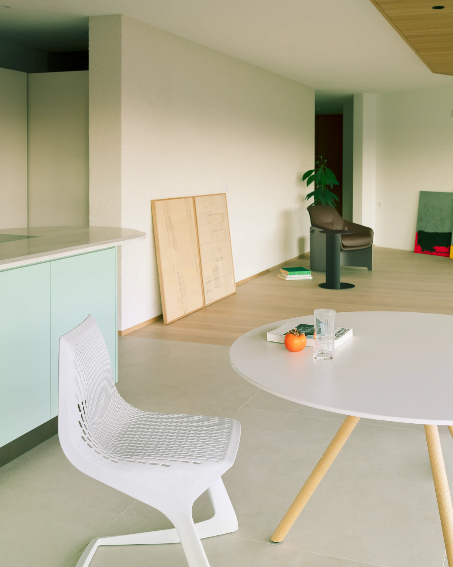 Casa Conte by Messner Architects — Interior view of the expanded Casa Conte reveals a minimalist open-plan living space with a white round table and organic-form white chair in the foreground.