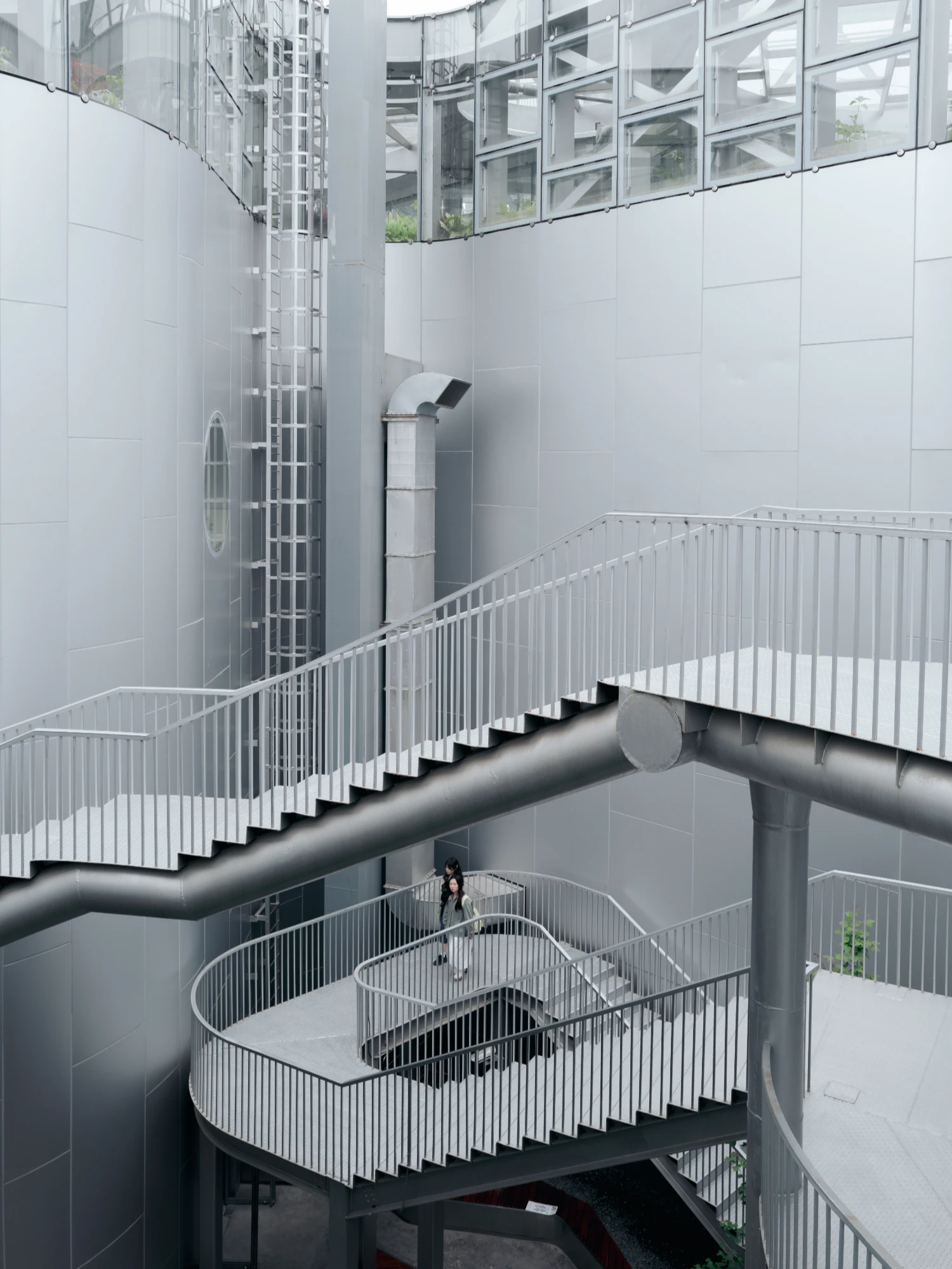 Expo Cultural Park Greenhouse Garden by Delugan Meissl captured by Marcus Yau — A spiral staircase descends through multiple levels of the greenhouse structure, its white metal balustrade creating a rhythmic vertical pattern against...