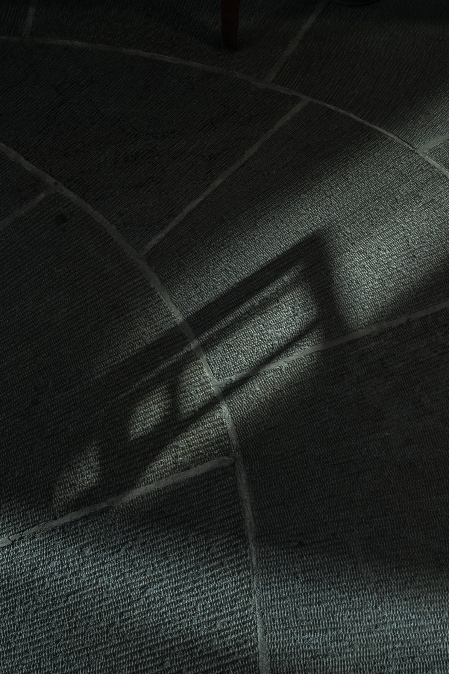 Woodland Cemetery Stockholm captured by Andy Liffner — Overhead view of dark textile surface divided by recessed linear grout lines forming a geometric grid pattern.