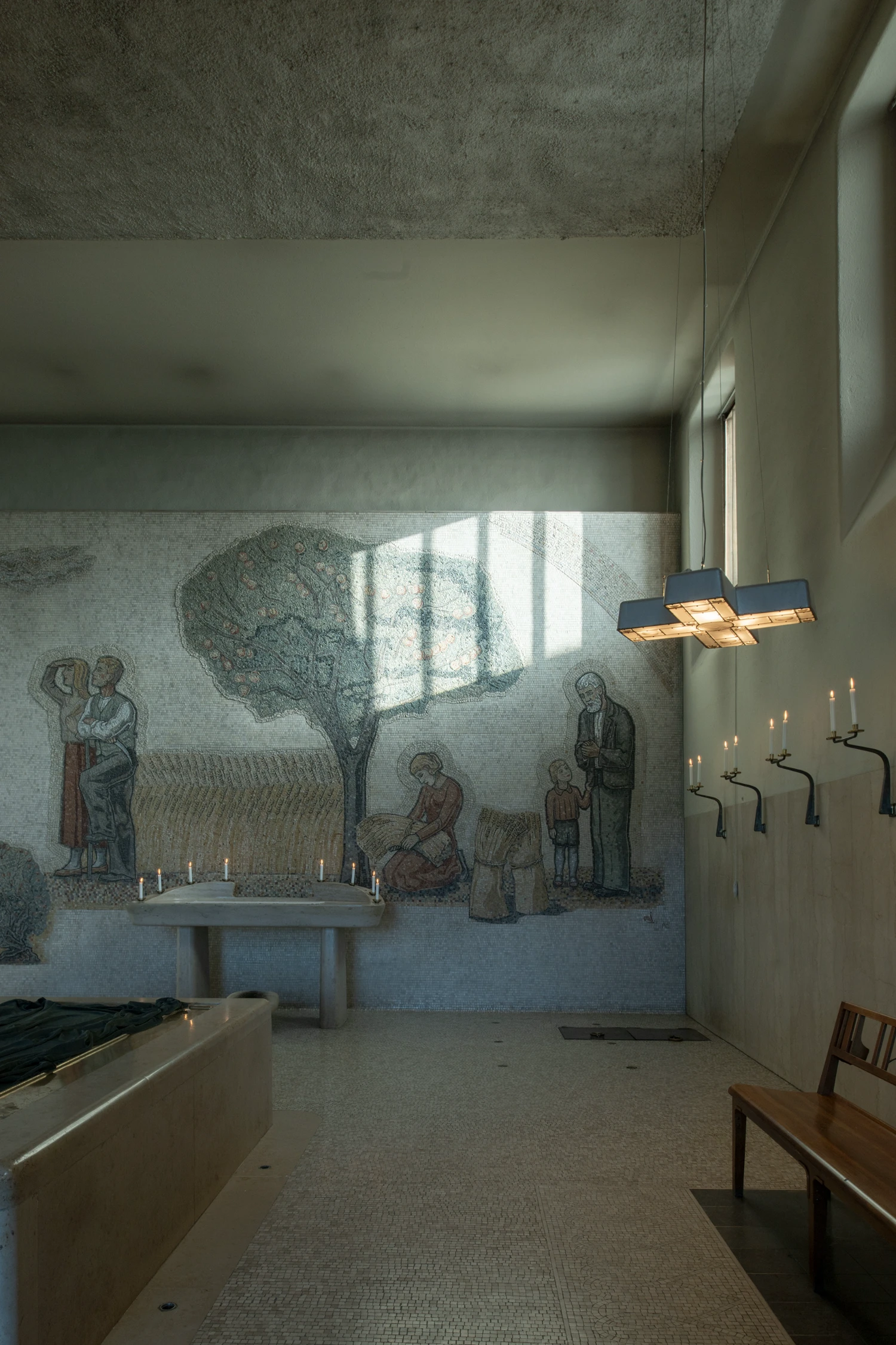 Woodland Cemetery Stockholm captured by Andy Liffner — A chapel interior bathed in directional sunlight streaming through a high window, casting sharp geometric shadows across rendered walls.