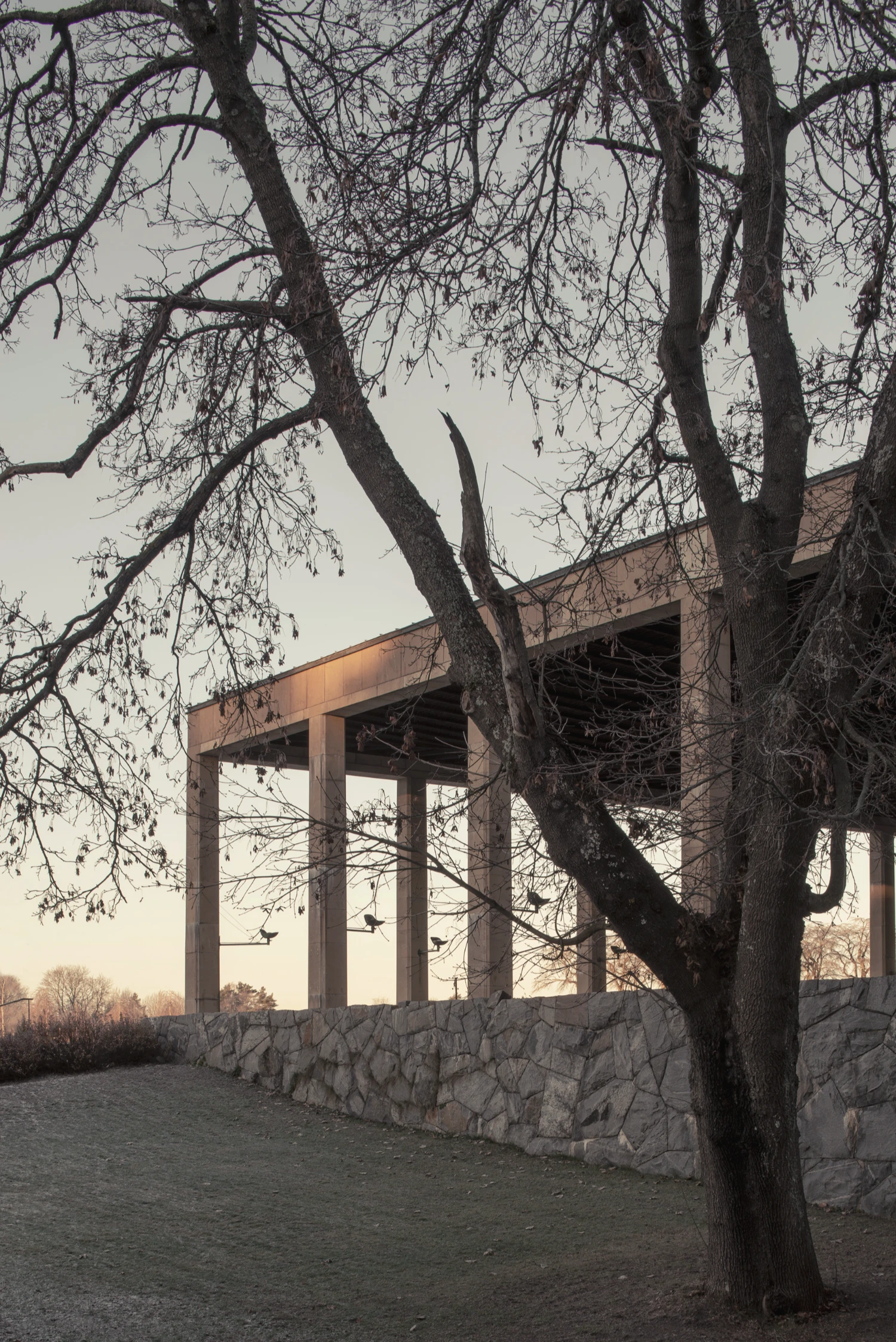 Woodland Cemetery Stockholm captured by Andy Liffner — A modernist stone and steel structure frames the winter landscape at Woodland Cemetery.