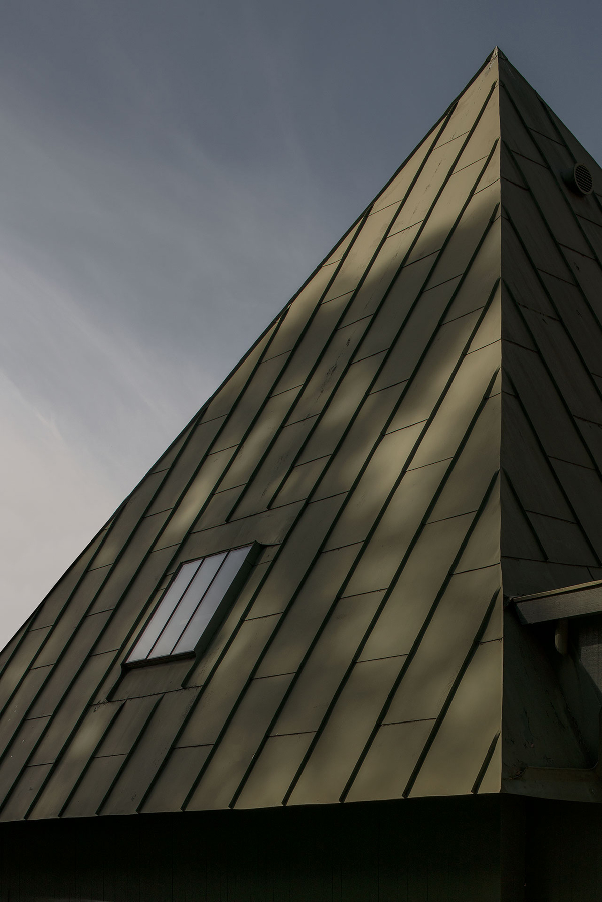 Woodland Cemetery Stockholm captured by Andy Liffner — Upward perspective of a pitched-roof chapel within Woodland Cemetery, revealing the geometric precision of its timber-clad exterior.