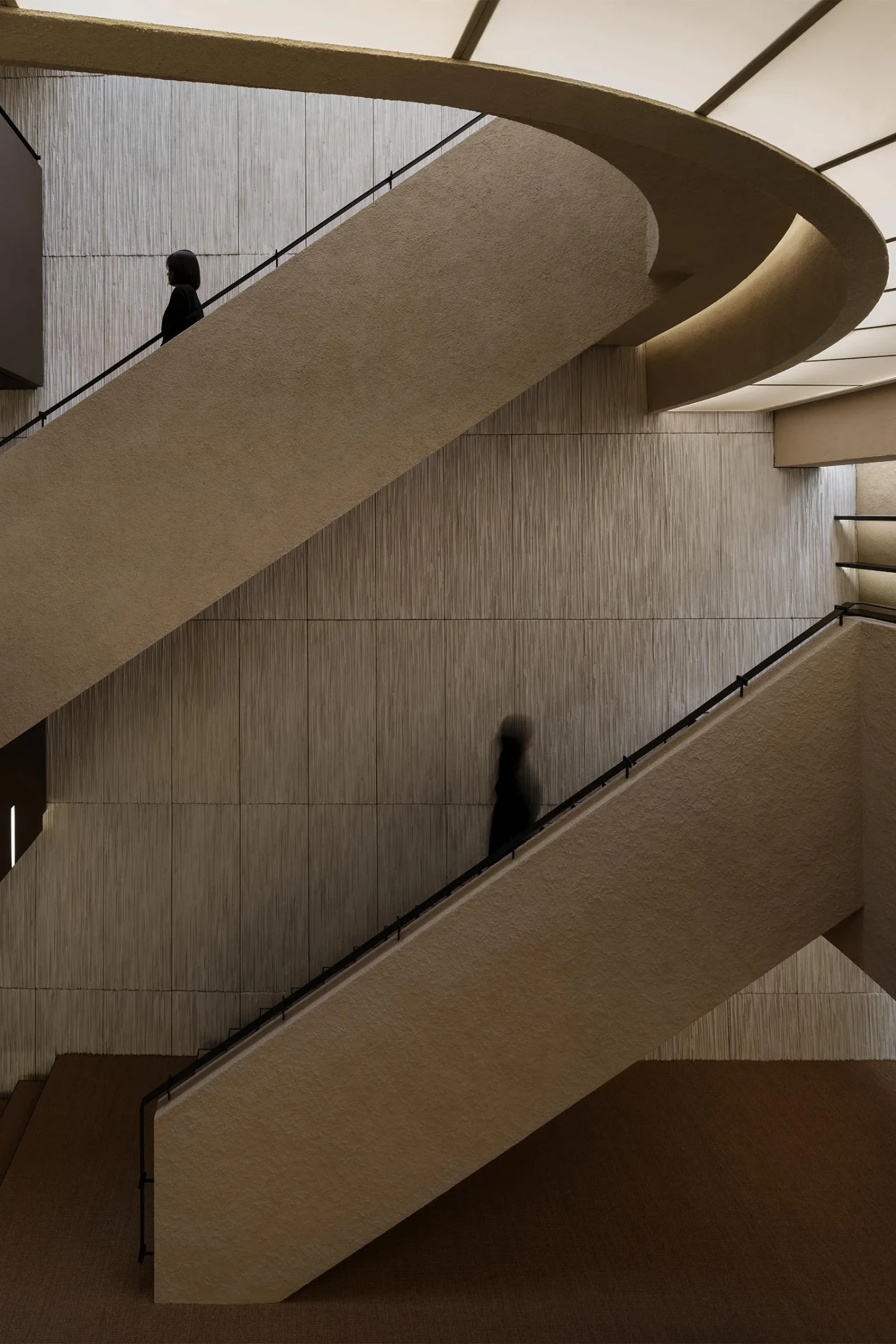 The Graphic bookstore by OONN Metaworks + U.LAB — Stacked cantilever sections of The Graphic bookstore reveal the building's sculptural interior staircase, where two figures traverse different levels.