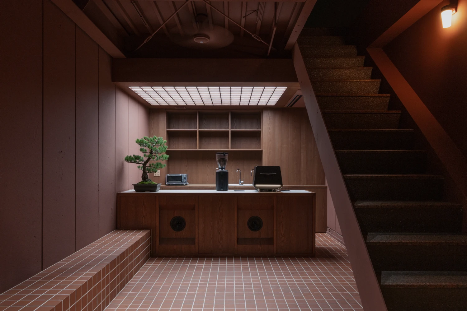uru coffee by TRANSFORM — A compact service counter anchors this ground-floor intervention, its timber cabinetry punctuated by two circular apertures and topped with minimal display...