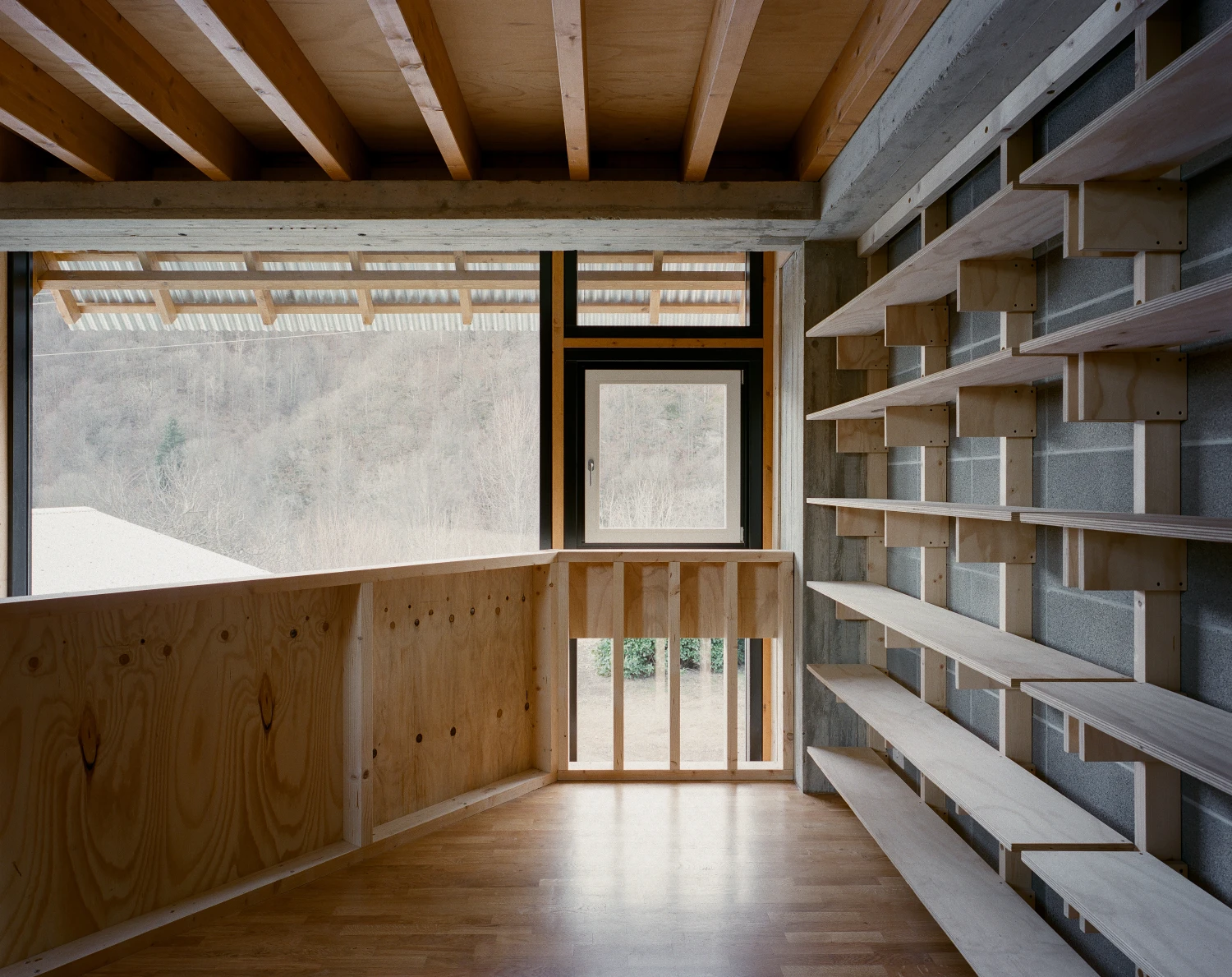 Casa BM by ErranteArchitetture — A timber-lined mezzanine interior reveals the project's constructive logic: exposed pine beam structure with deep overhanging eaves, full-height glazing...