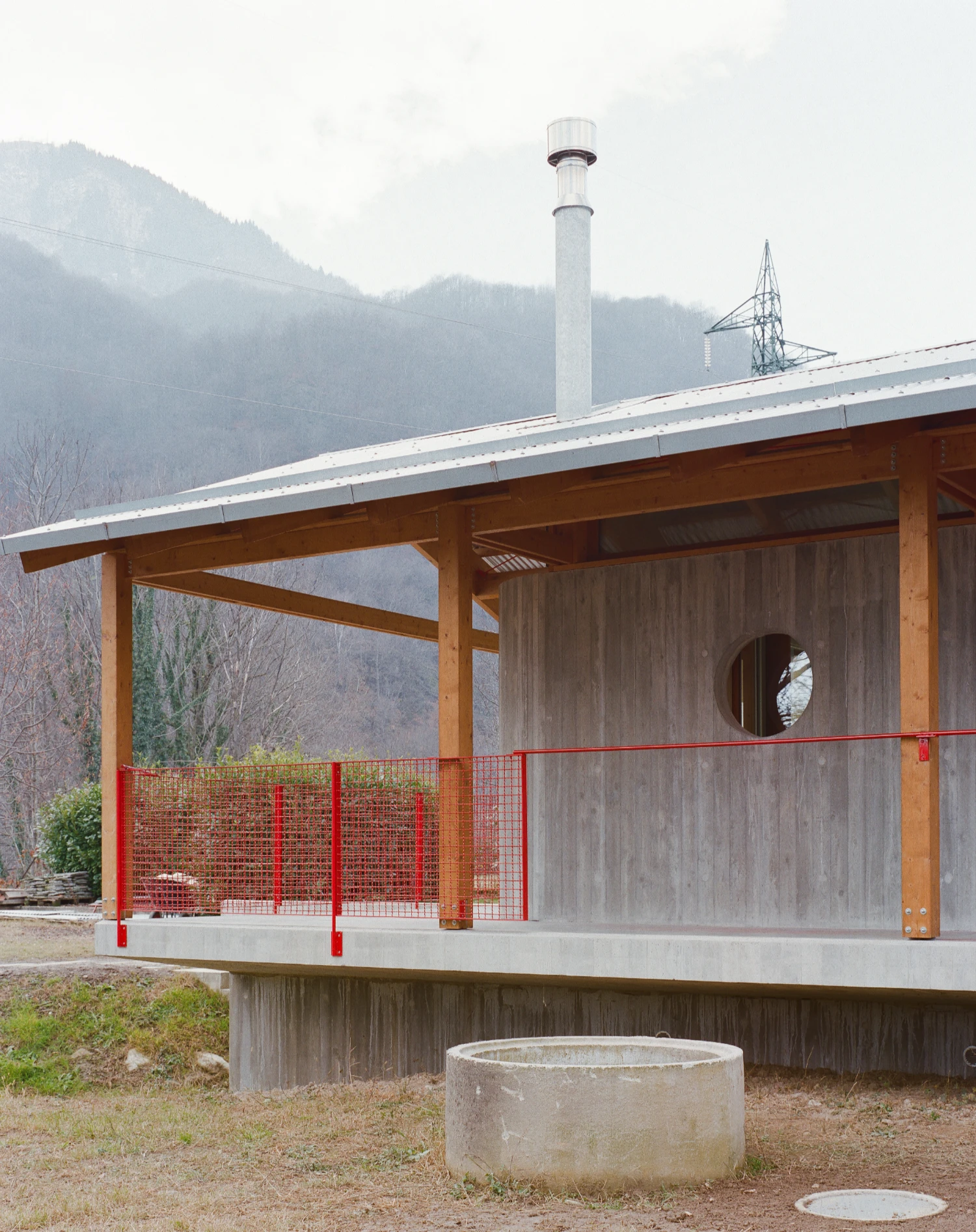 Casa BM by ErranteArchitetture — A timber-framed pavilion extends from an existing structure on a concrete platform elevated on pilotis.