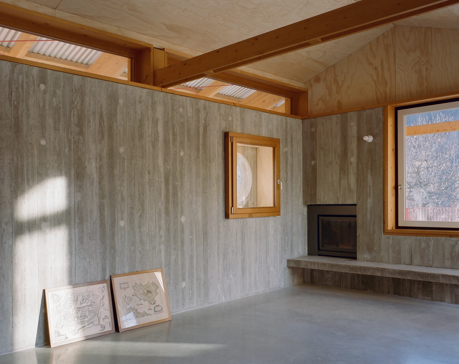 Casa BM by ErranteArchitetture — A pavilion interior reveals timber beam structure against board-formed concrete walls in grey-toned finish.