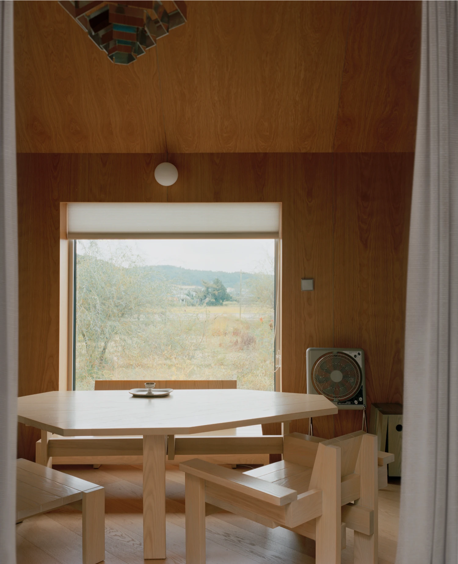 Hoji Gangneung Houses by AOA Architects captured by Danny Kai — Interior view of a dining pavilion framed by a substantial timber-clad opening.