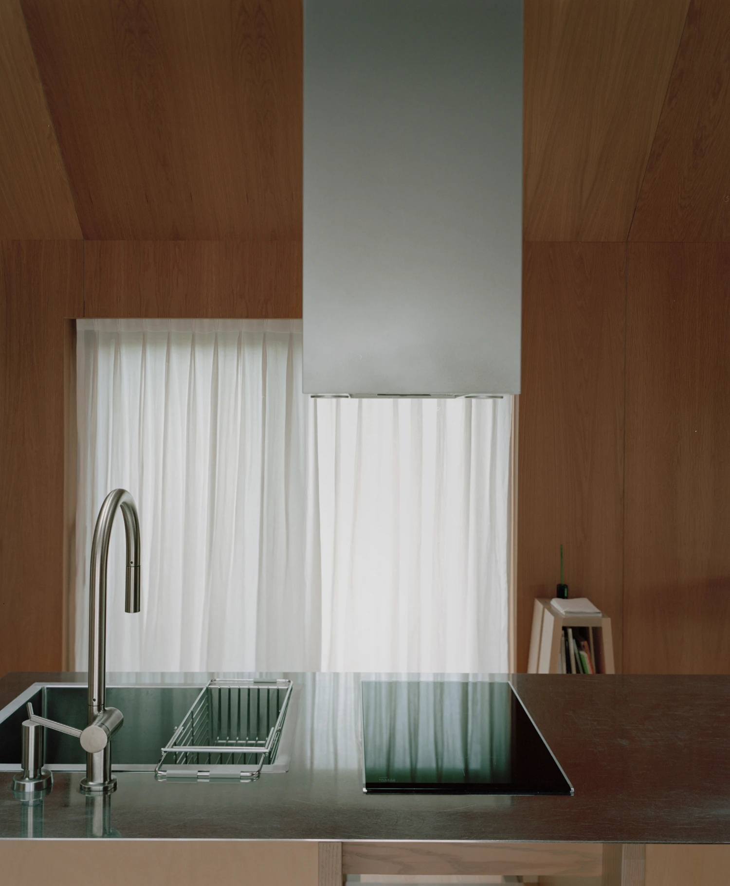 Hoji Gangneung Houses by AOA Architects captured by Danny Kai — A kitchen counter anchors this interior view, its dark surface hosting a curved chrome faucet and wire basket.