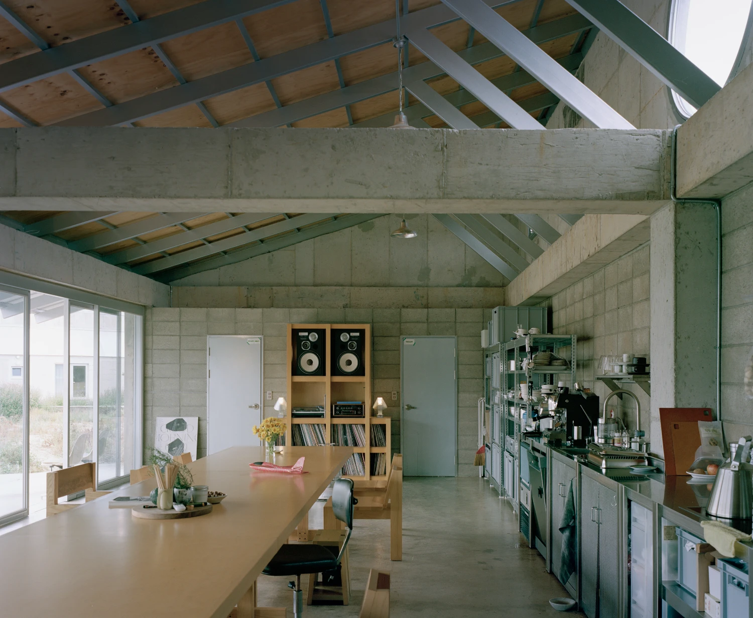 Hoji Gangneung Houses by AOA Architects captured by Danny Kai — Interior view of an open-plan living and kitchen space defined by exposed timber roof trusses and board-formed concrete beams.
