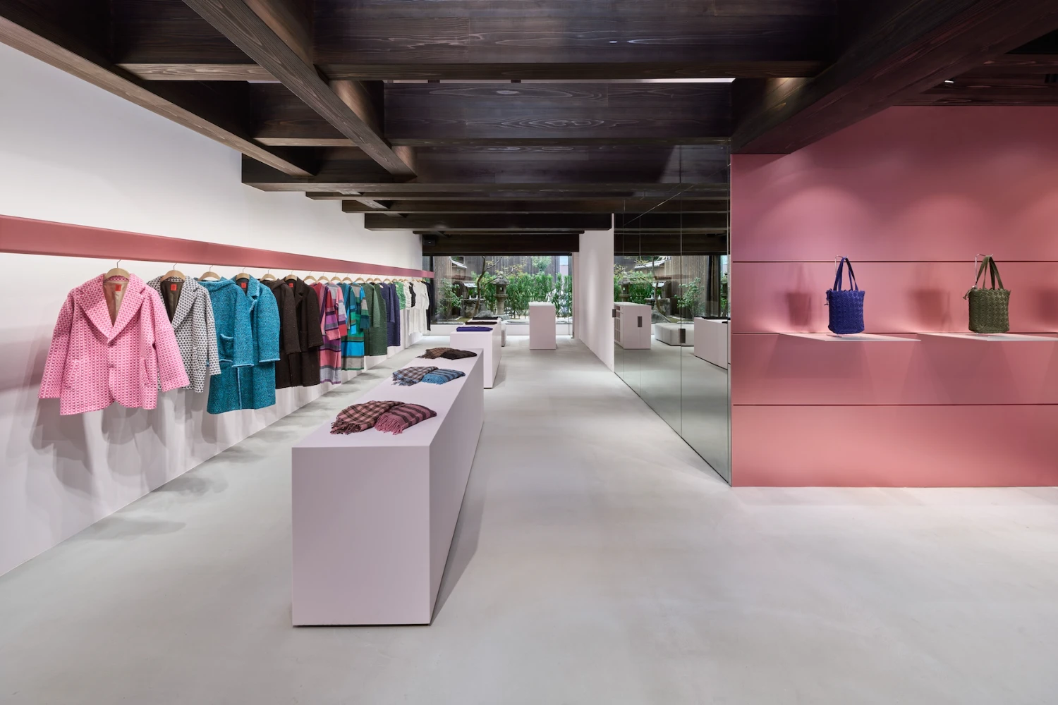 Issey Miyake HaaT flagship in Kyoto by Tokujin Yoshioka — Interior view of the HaaT flagship reveals a minimalist retail environment anchored by white display pedestals arranged in linear formation.