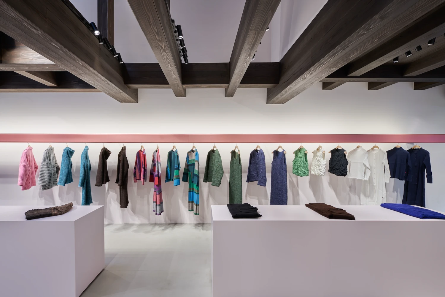 Issey Miyake HaaT flagship in Kyoto by Tokujin Yoshioka — The interior display wall showcases a linear arrangement of draped textiles hung from a continuous rail, creating a systematic presentation of Issey...