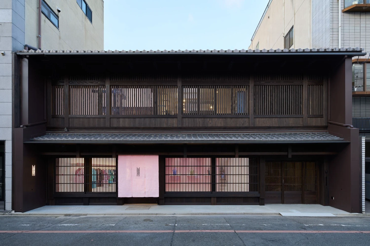 Issey Miyake HaaT flagship in Kyoto by Tokujin Yoshioka — The Issey Miyake HaaT flagship presents a two-story timber facade organized by vertical lattice screens in charcoal-toned wood.