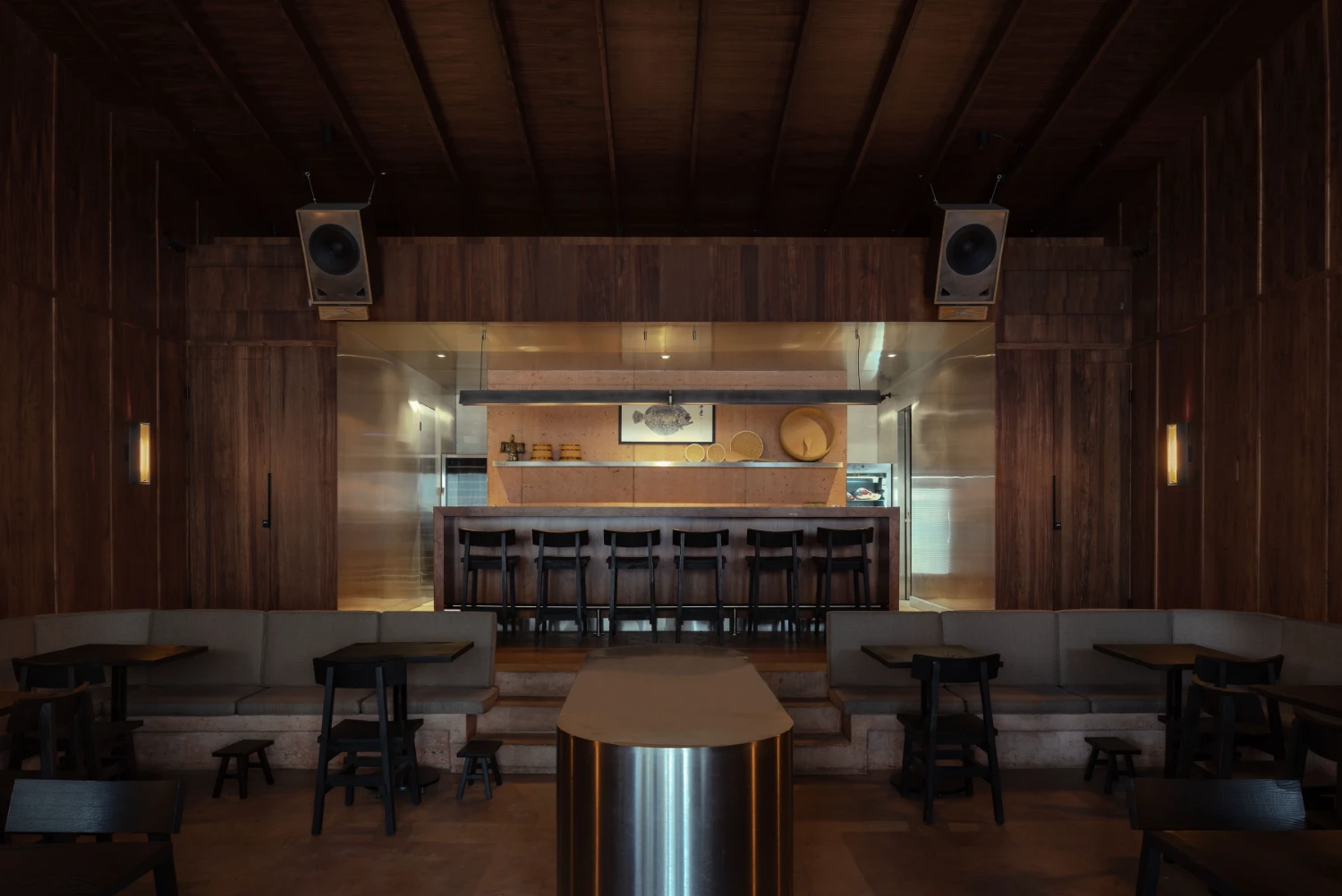 ZUKE Restaurant by Sofía Betancur + Taller Nacional — The sushi counter serves as the spatial and visual anchor of ZUKE's dining hall, a brushed-steel cylinder wrapped in wood-grain veneer that organizes the...