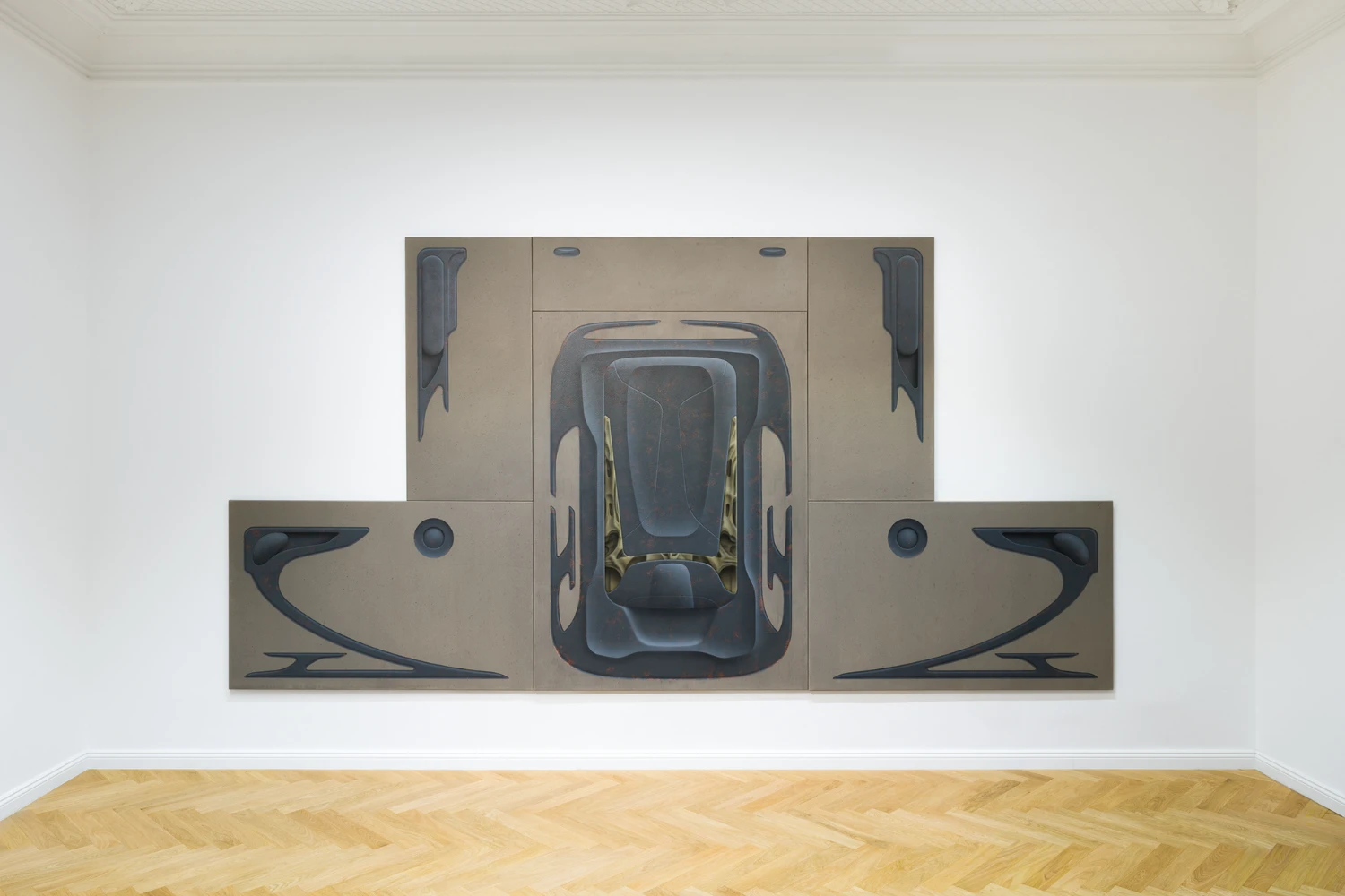Bloom by Tomáš Absolon Milan Vagač at SPOT Gallery — A multi-panel wall installation dominates the gallery space, presenting an overhead perspective of a vehicle rendered in dark charcoal tones against beige...